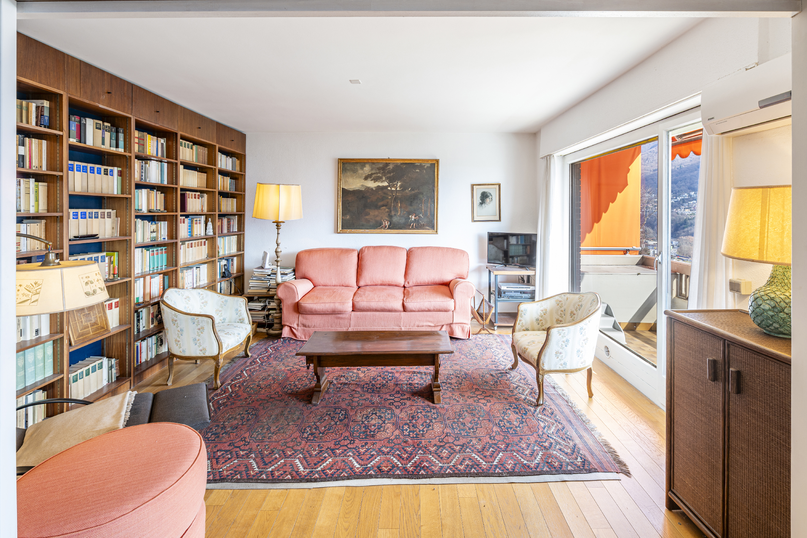 Wohnzimmer mit Bibliothekswand und Balkonblick