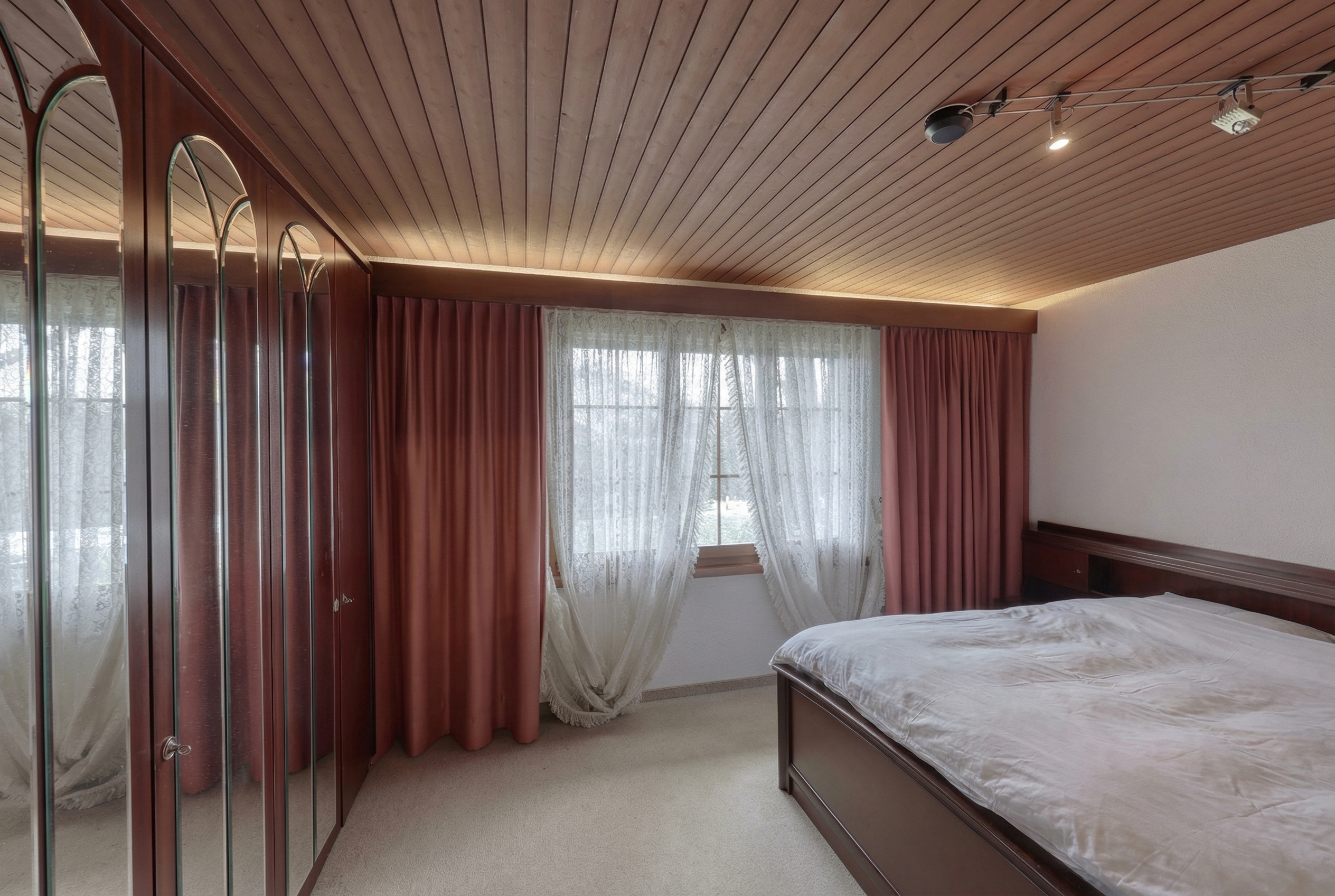 Schlafzimmer mit Holzdecke und Spiegelschrank