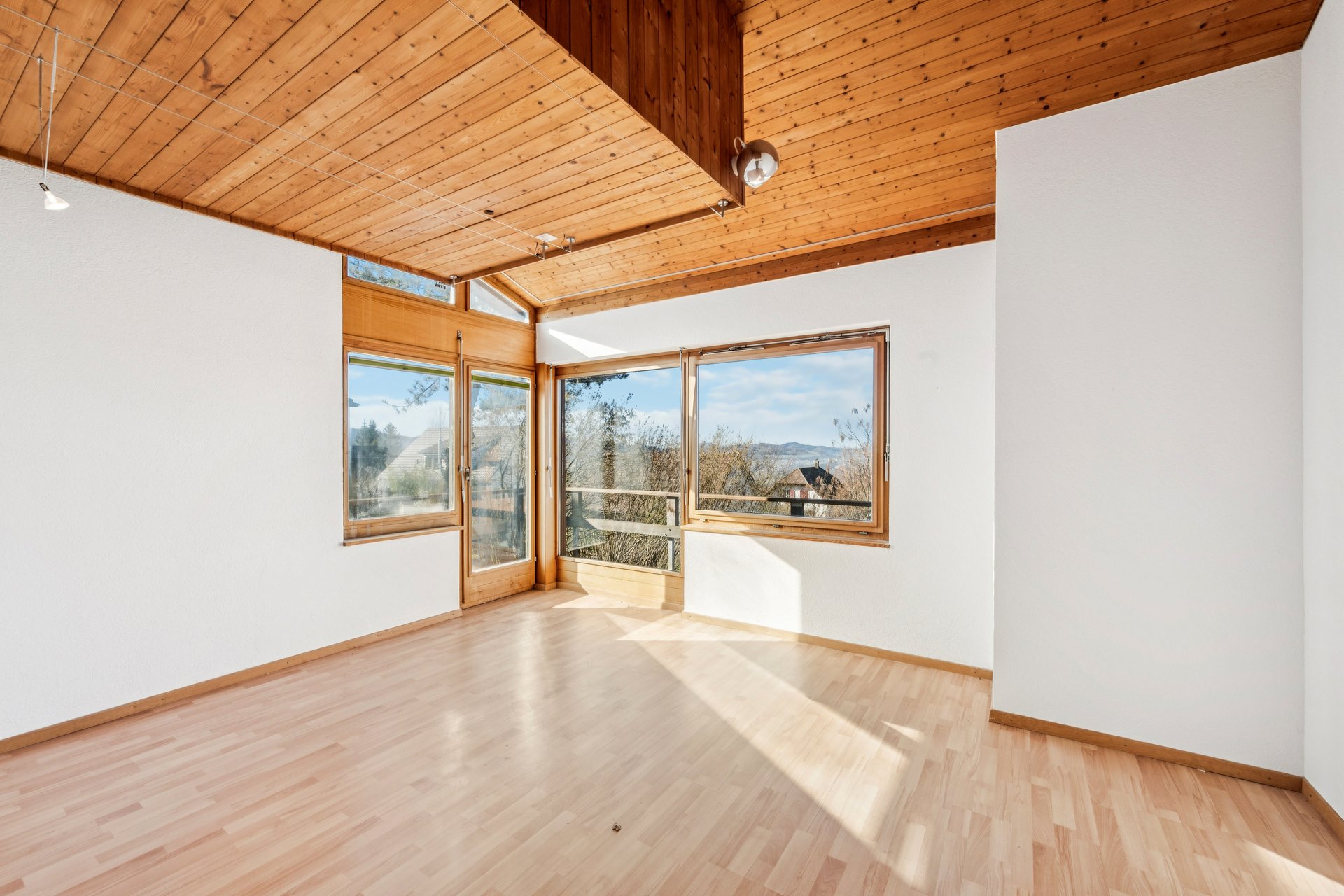 Heller leerer Raum mit großen Holzfenstern und Holzdecke