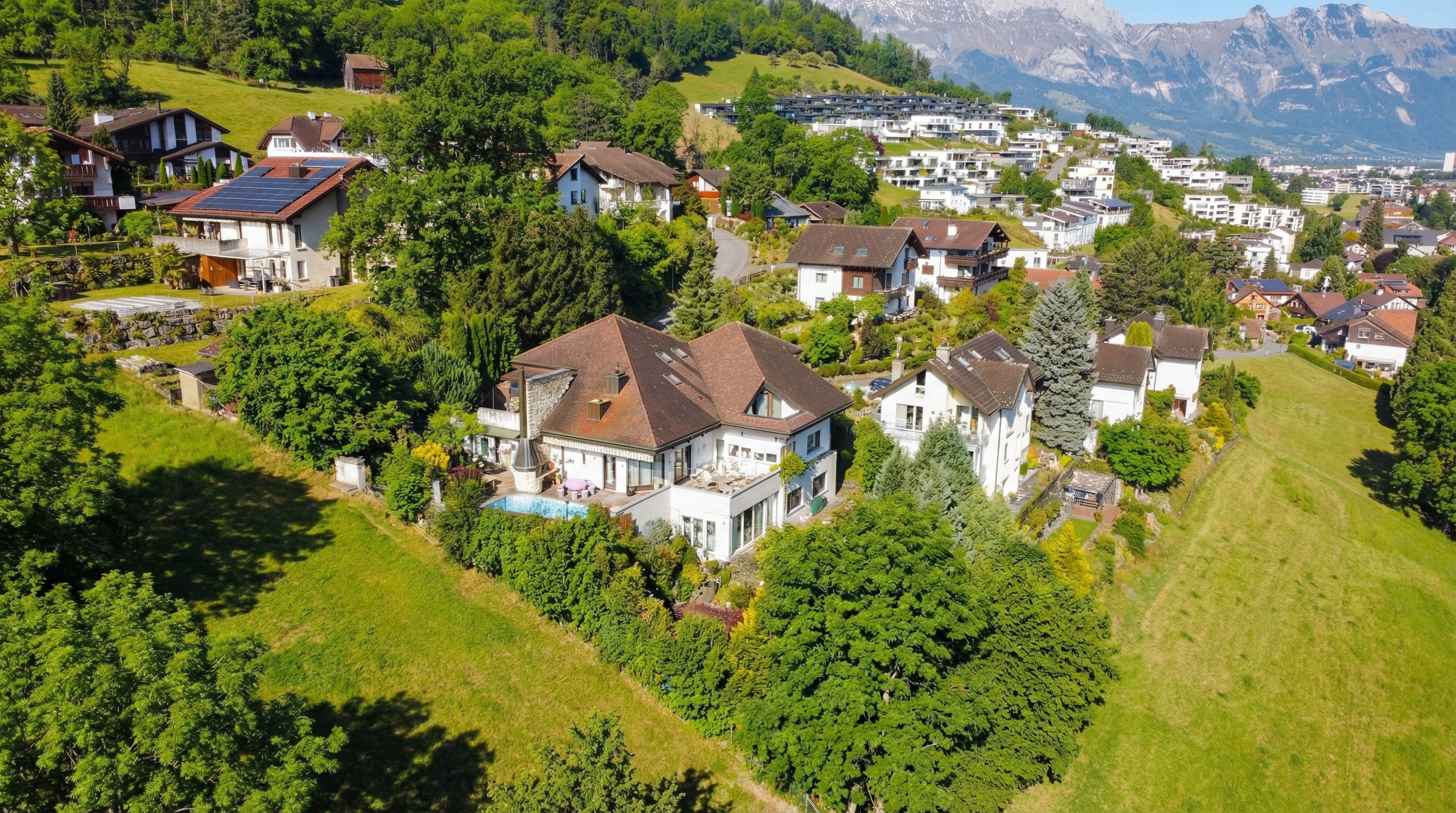 Luftaufnahme einer Wohnsiedlung am Hang mit Bergpanorama