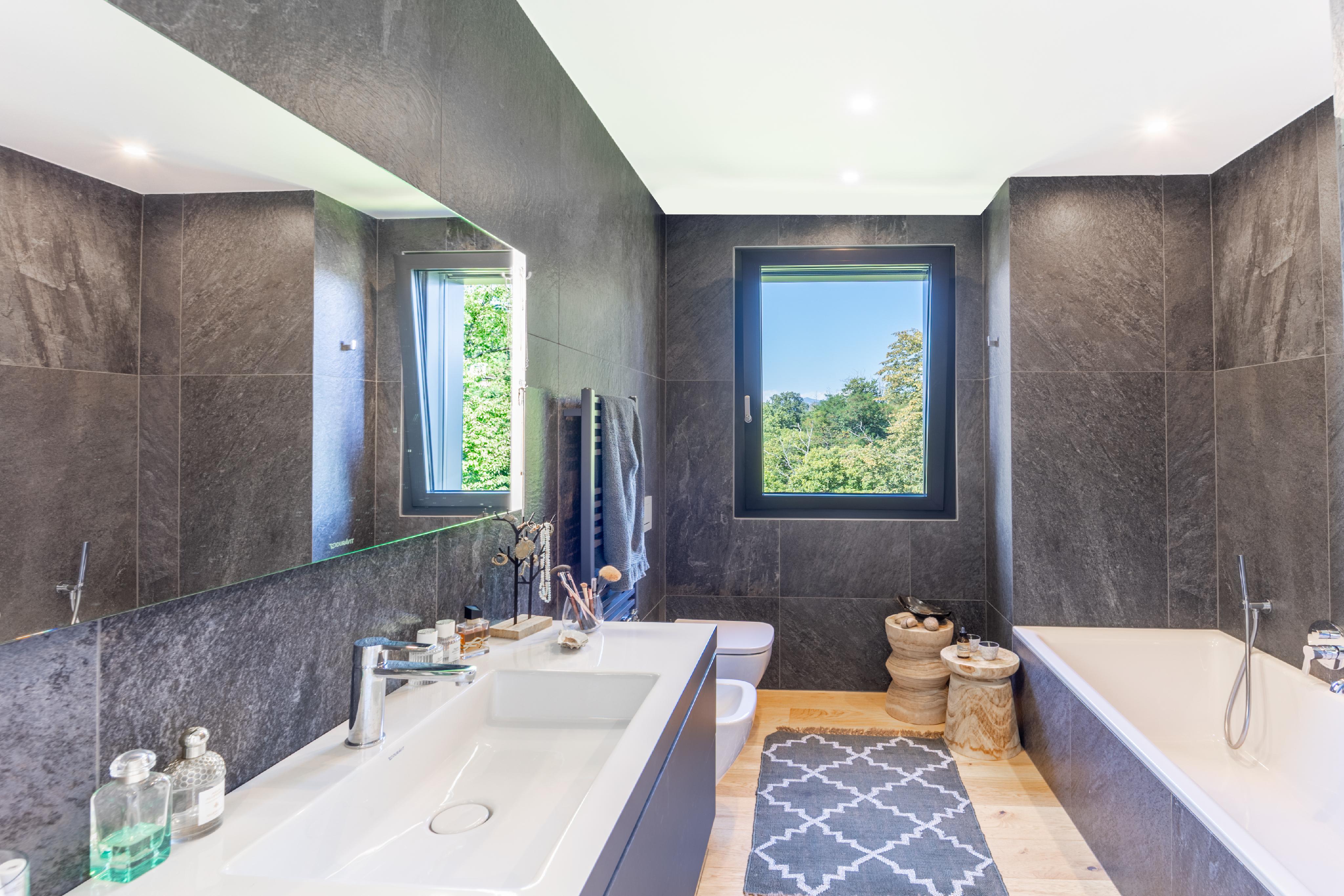 Modernes Badezimmer mit dunkler Steinoptik und freistehender Wanne