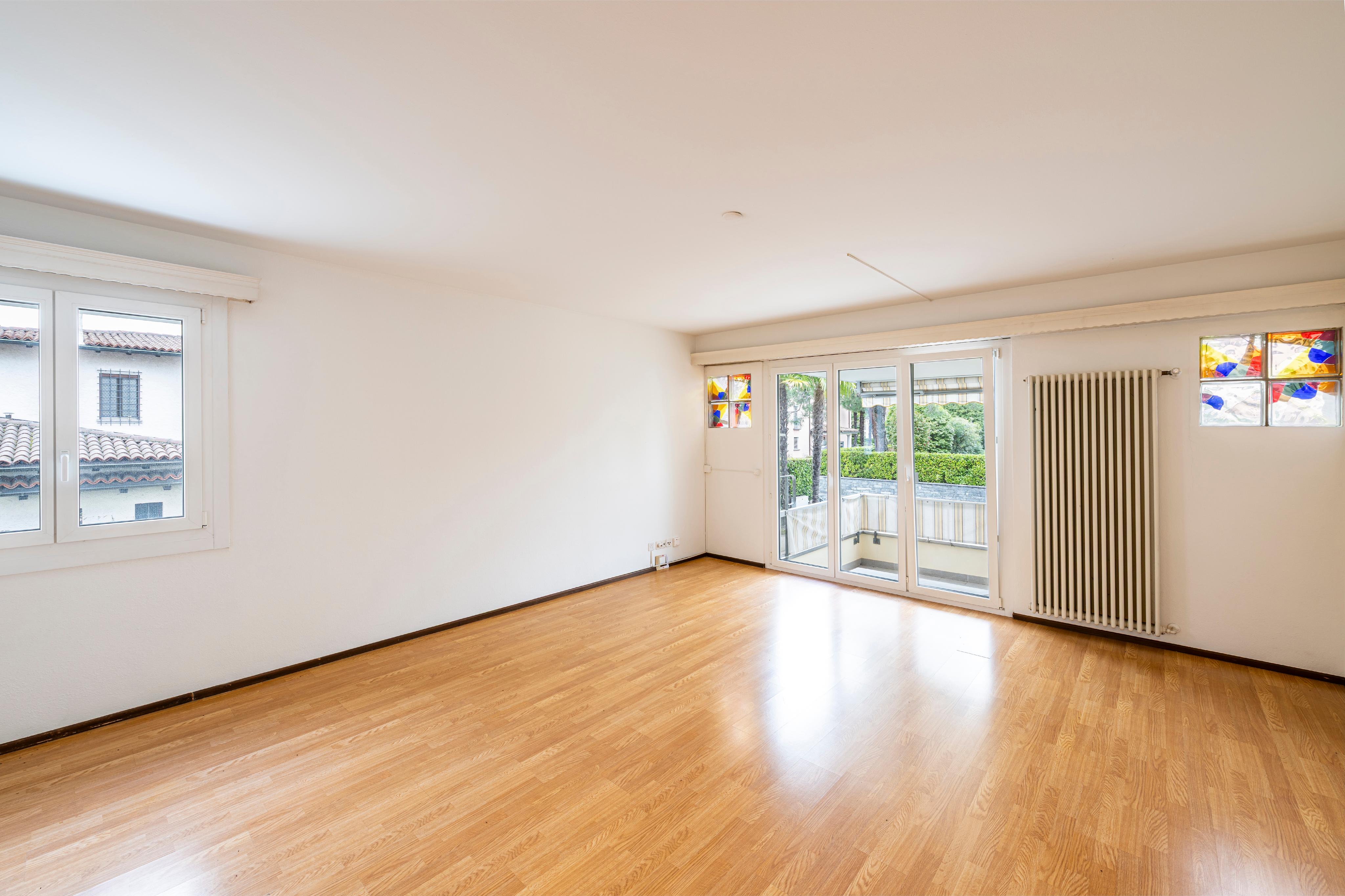 Heller leerer Wohnraum mit Balkon und großen Fenstern