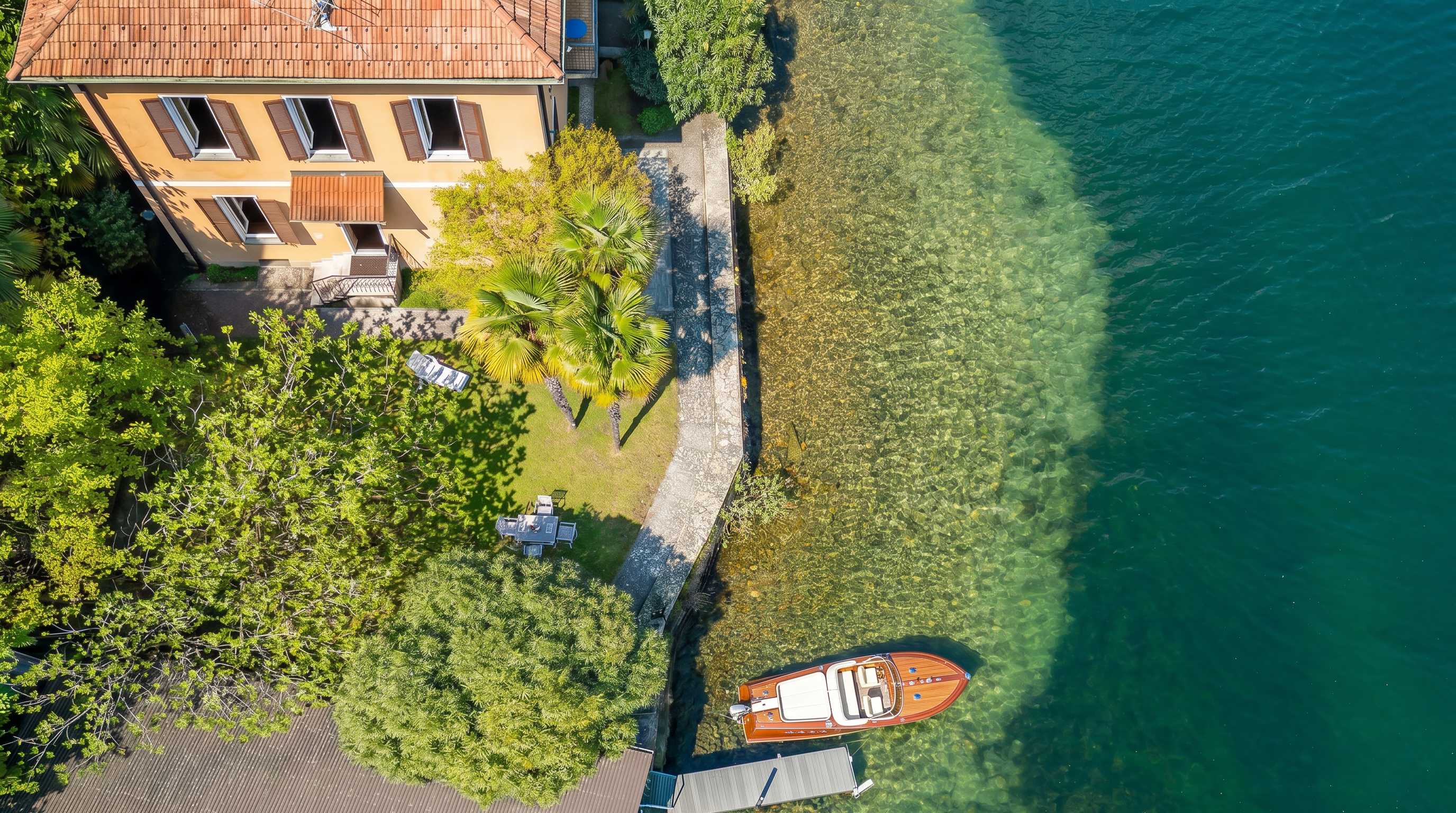 Luftaufnahme einer Uferimmobilie mit Garten und Bootsanleger
