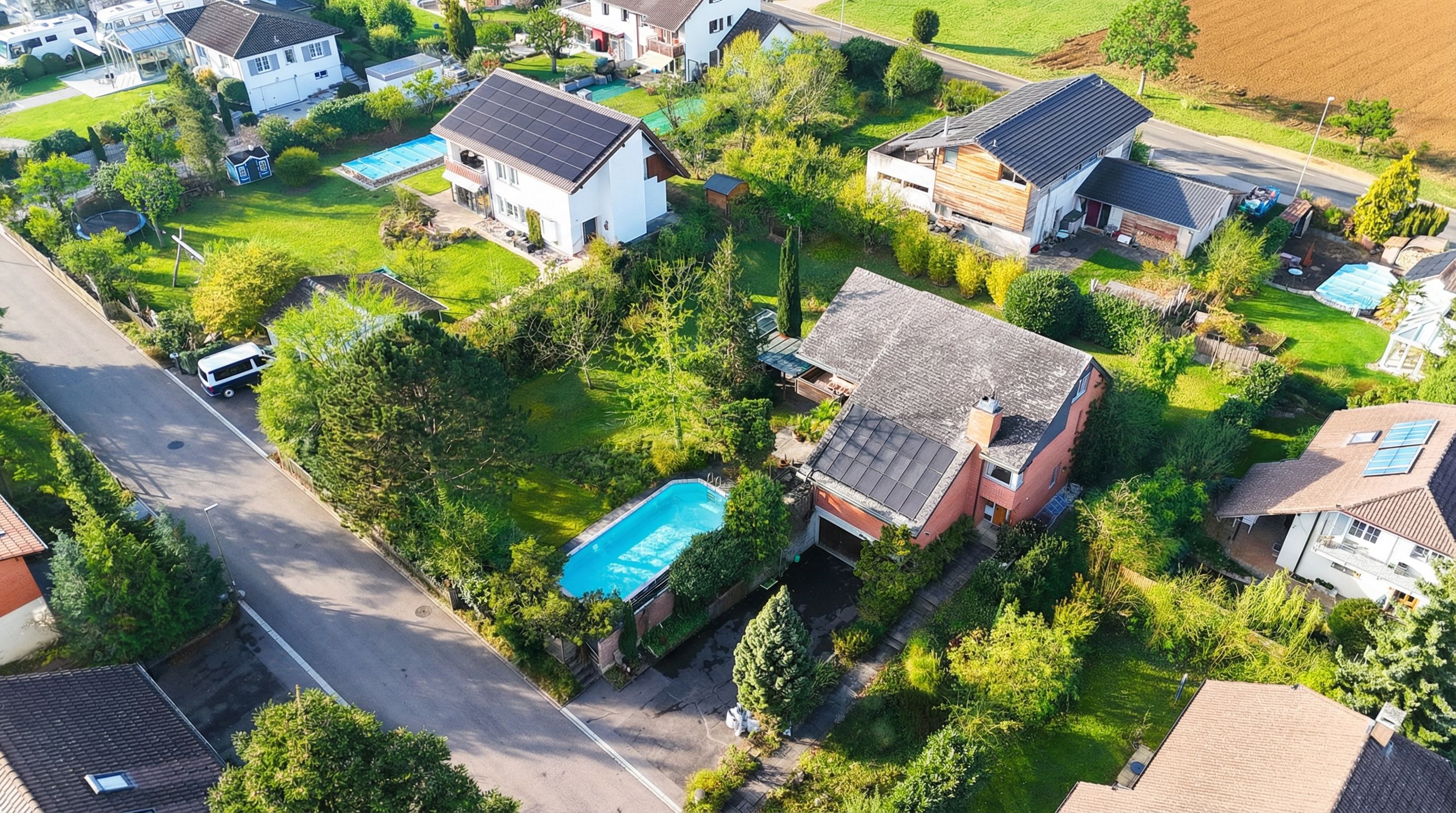 Luftaufnahme eines Wohngebiets mit Häusern, Gärten und Pool