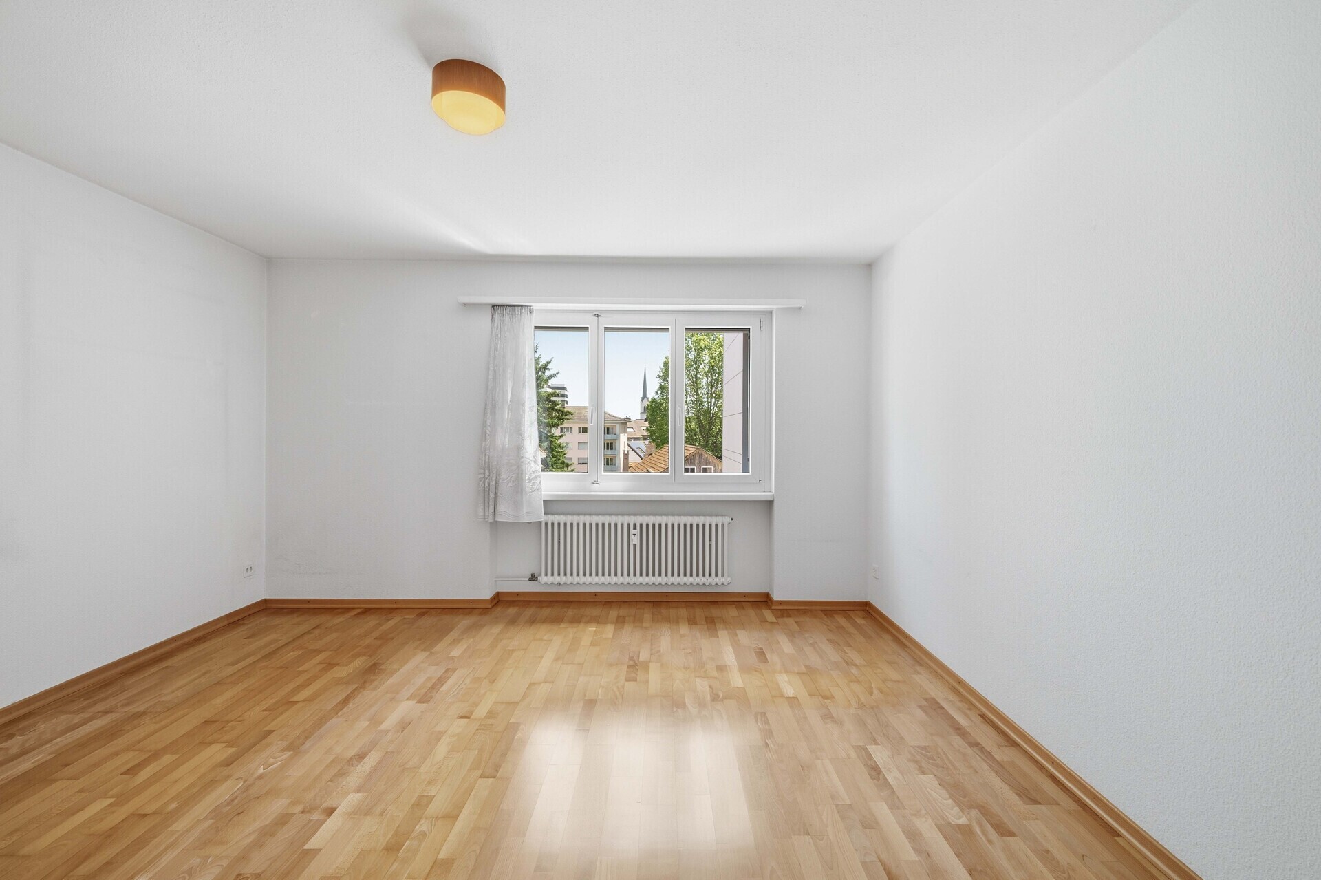 Leerer Wohnraum mit Fenster und Parkettboden