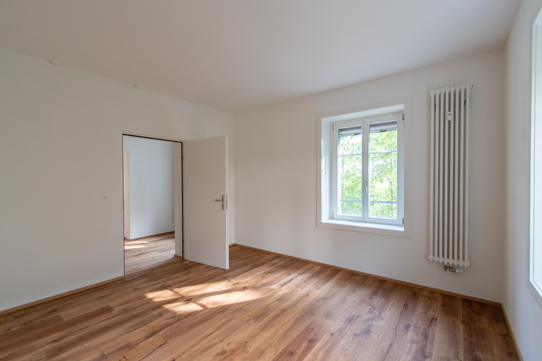 Heller leerer Raum mit Holzboden und Fenster