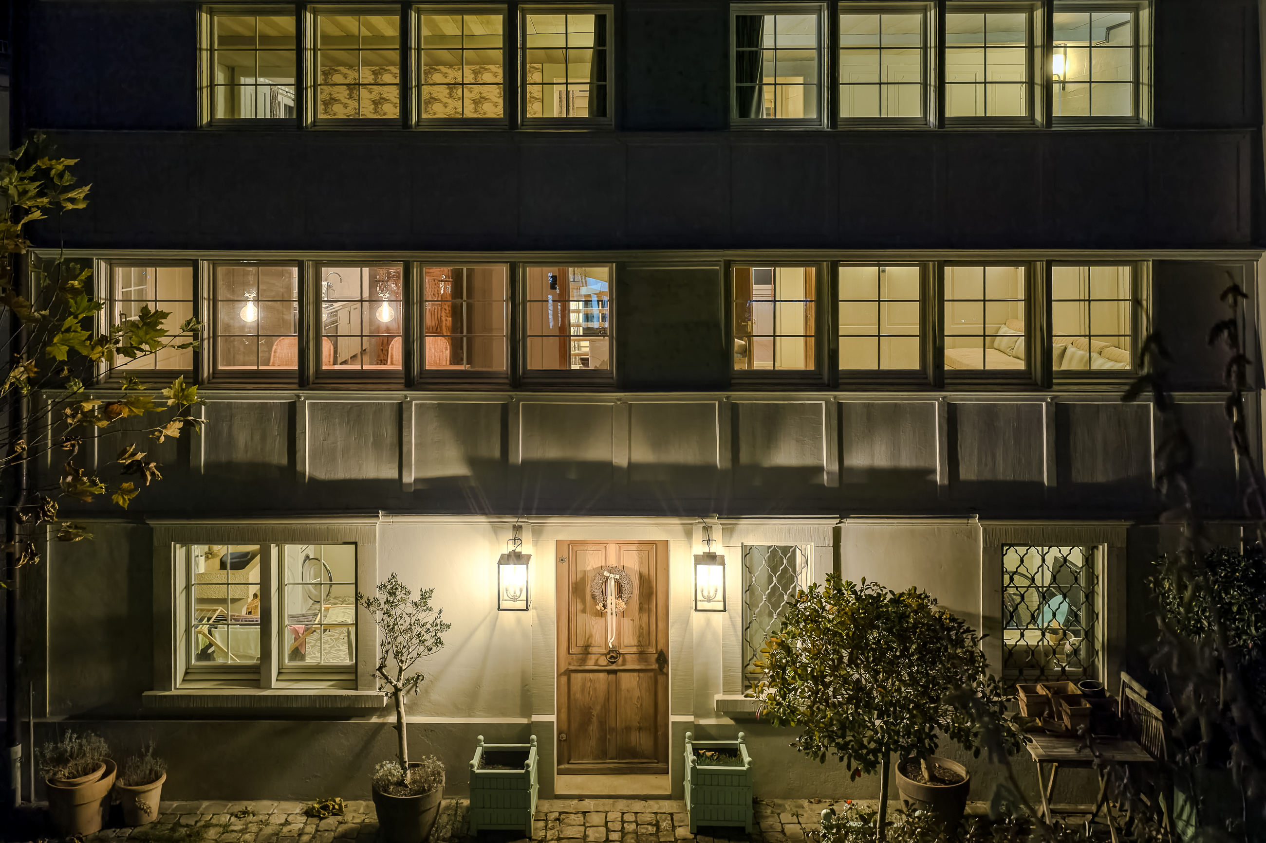 Nächtliche Hausfassade mit beleuchteten Fenstern