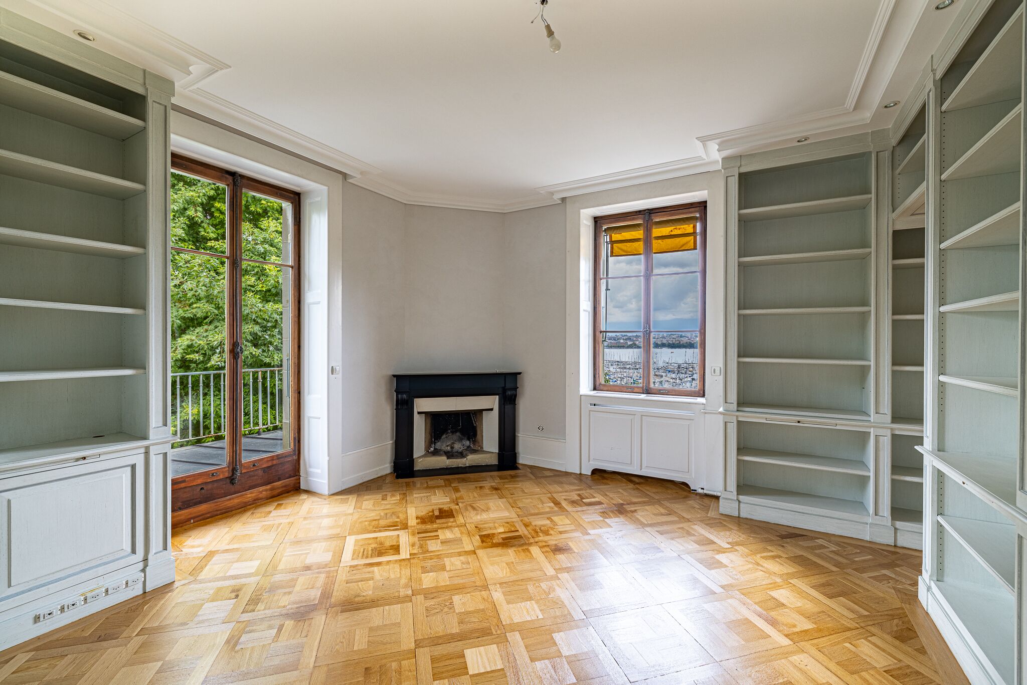 Eleganter Raum mit Kamin, Parkett und Einbauregalen