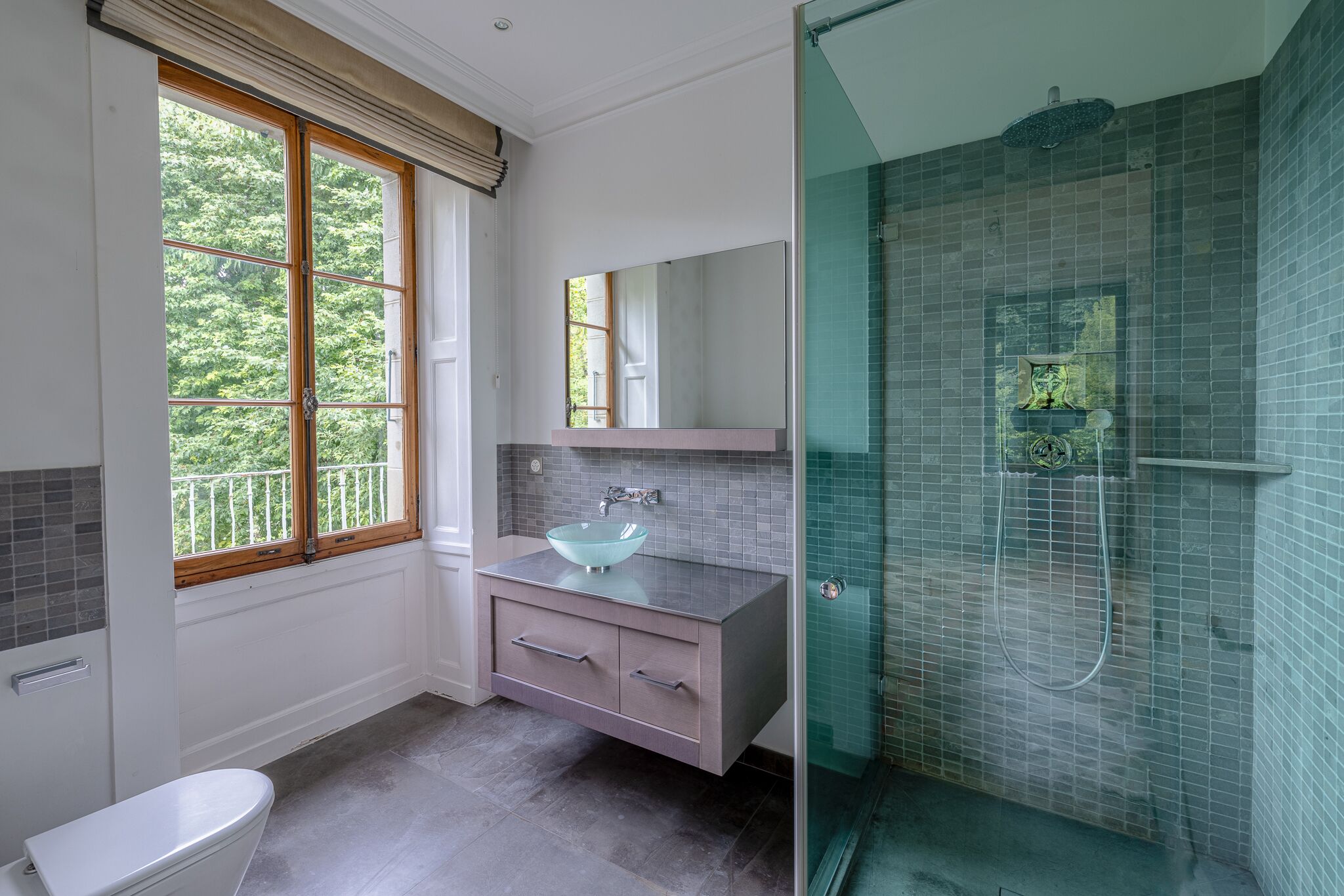 Modernes Badezimmer mit Glasdusche und Fensterblick ins Grüne
