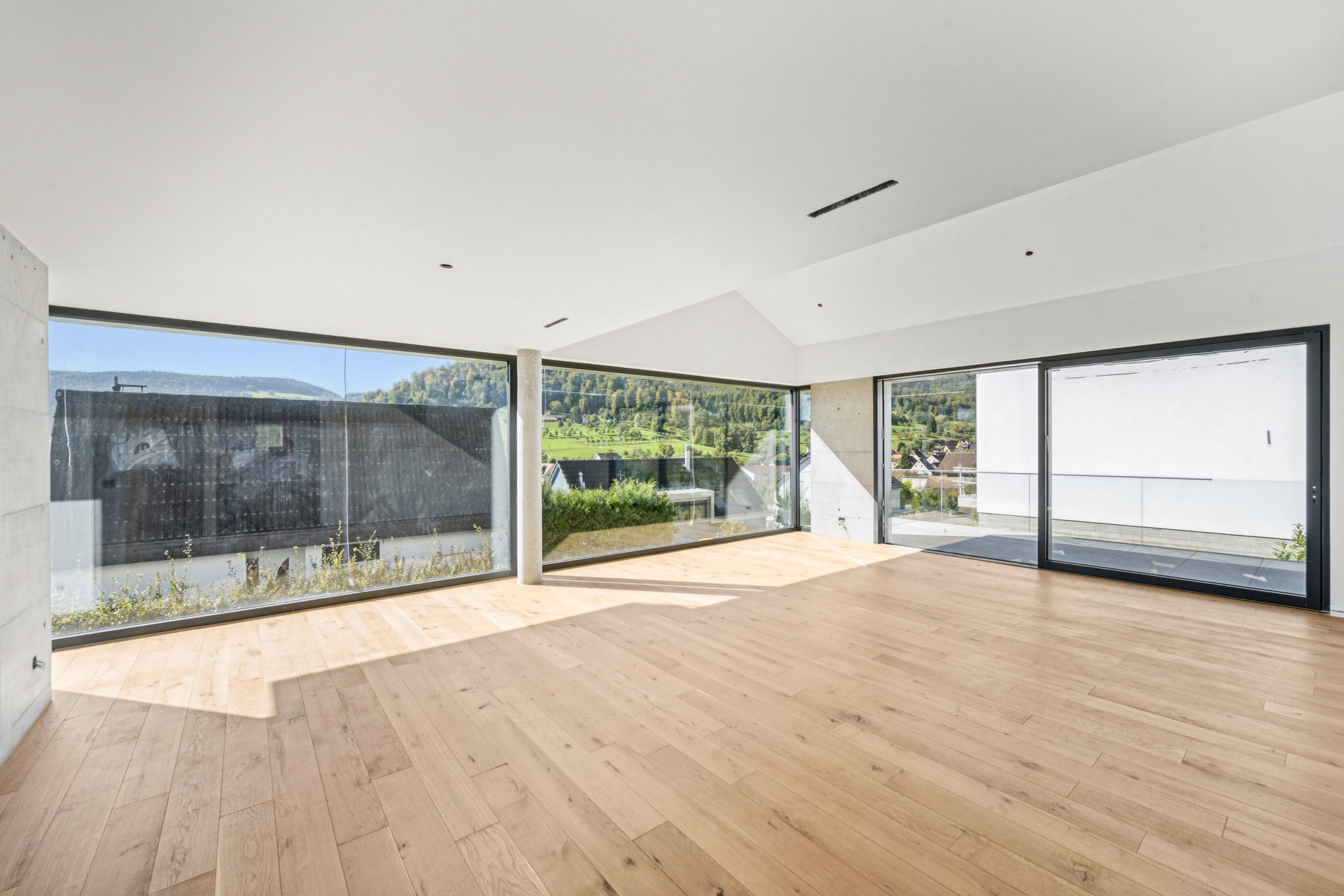 Heller leerer Wohnraum mit Panoramafenstern und Holzparkett