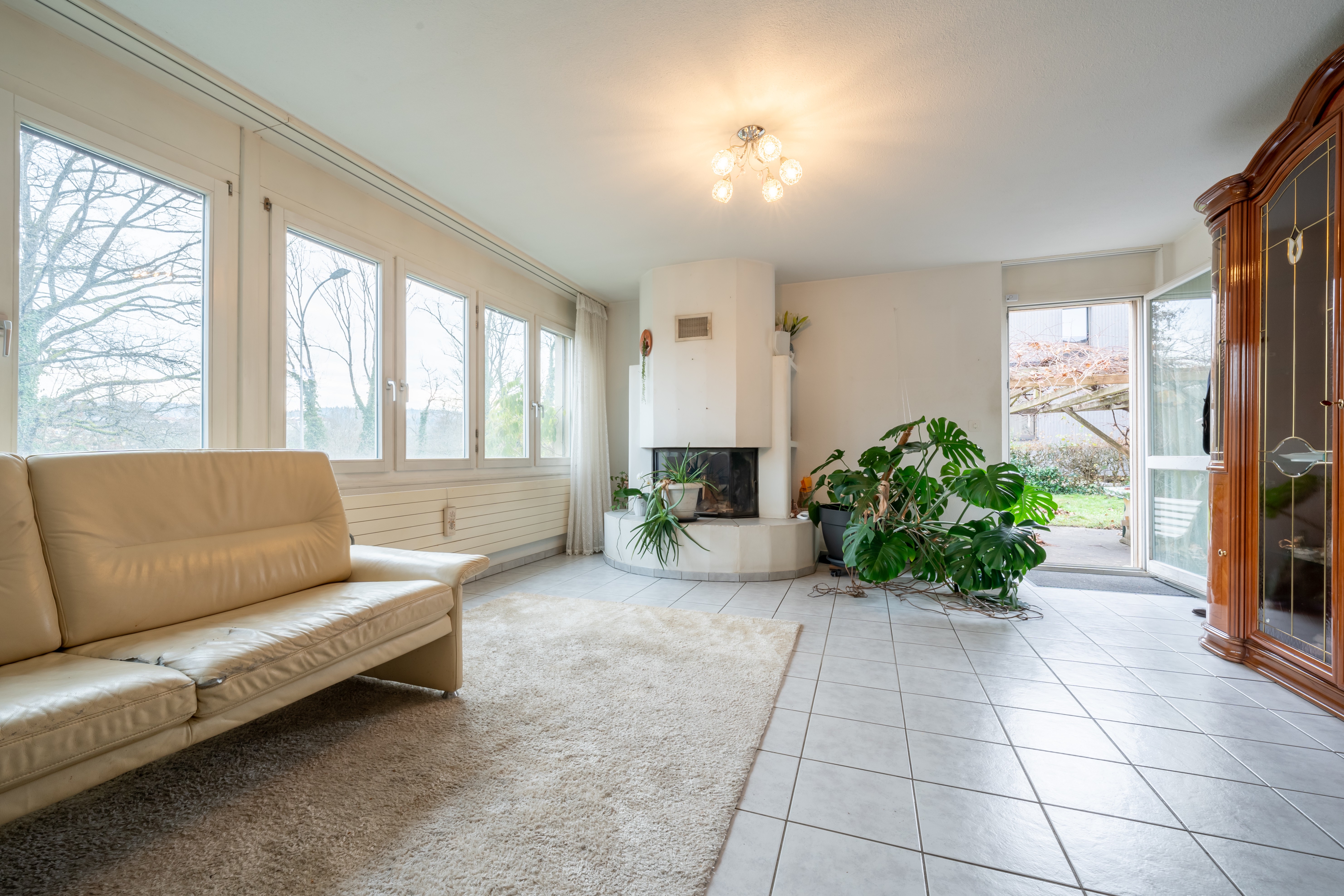 Helles Wohnzimmer mit Kamin und großen Fenstern