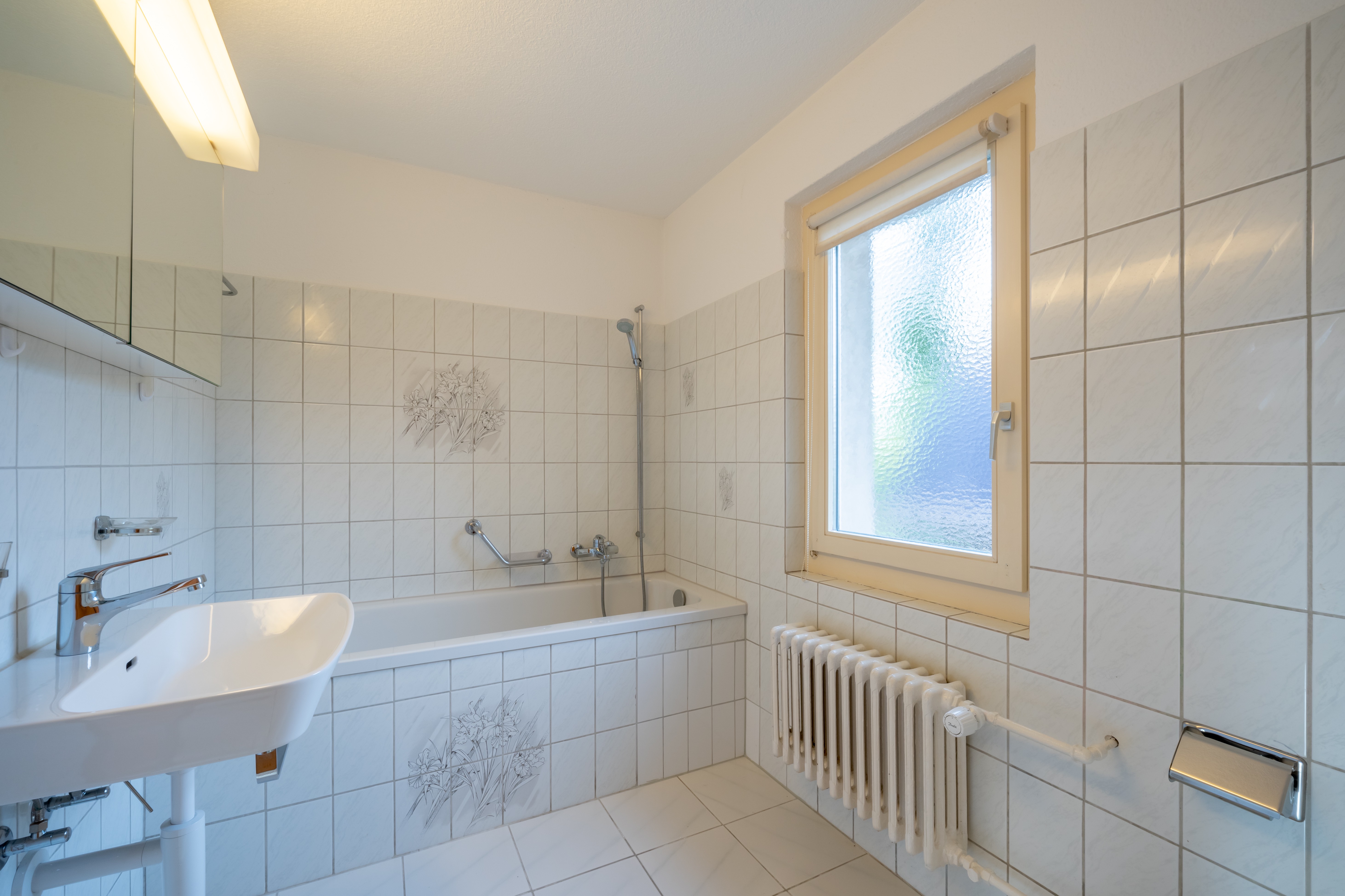 Helles Badezimmer mit Badewanne und Fenster