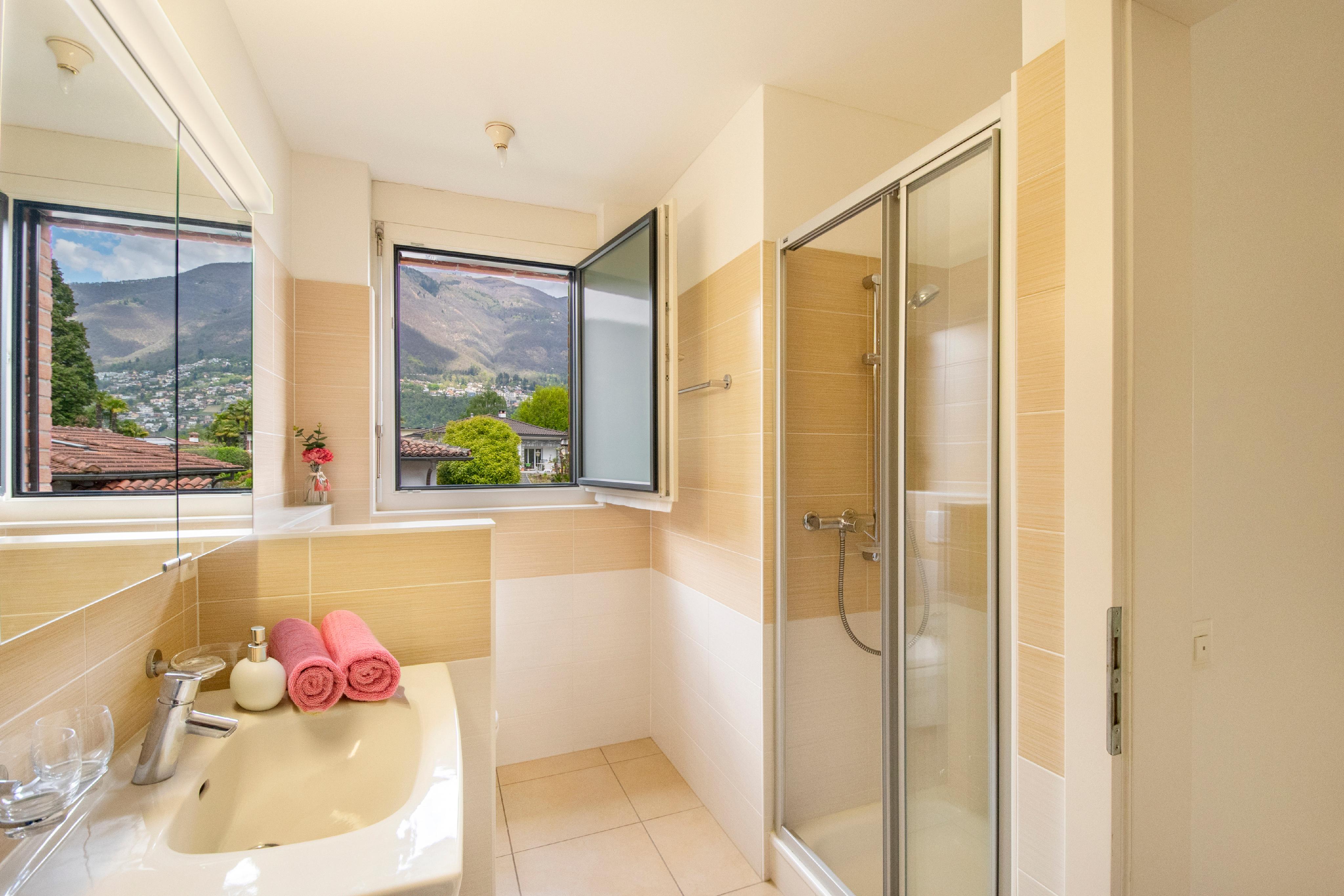 Helles Badezimmer mit Dusche und Bergblick