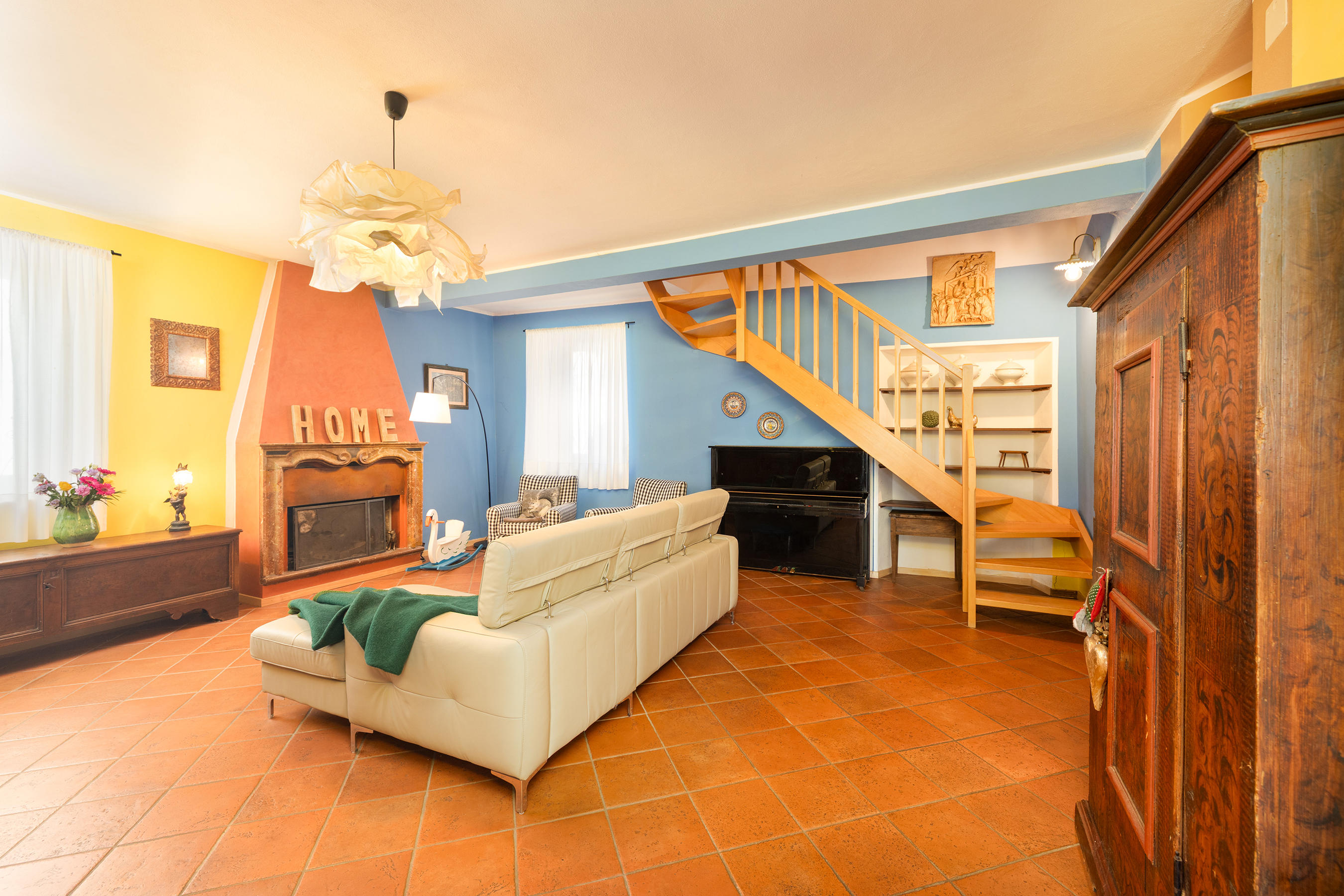 Farbenfrohes Wohnzimmer mit Kamin und Holztreppe