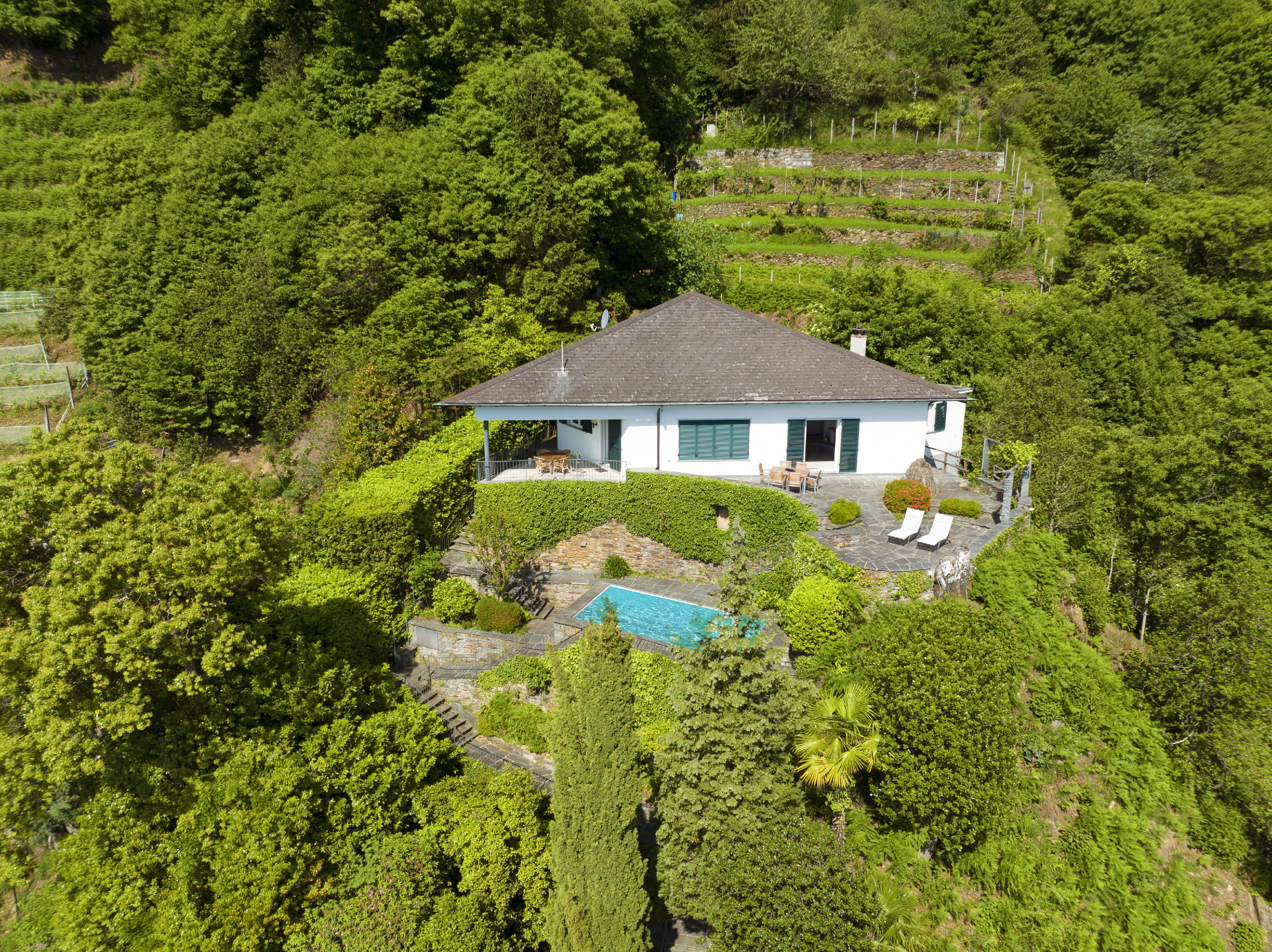 Luftaufnahme eines Hauses mit Pool in üppiger Hügellandschaft
