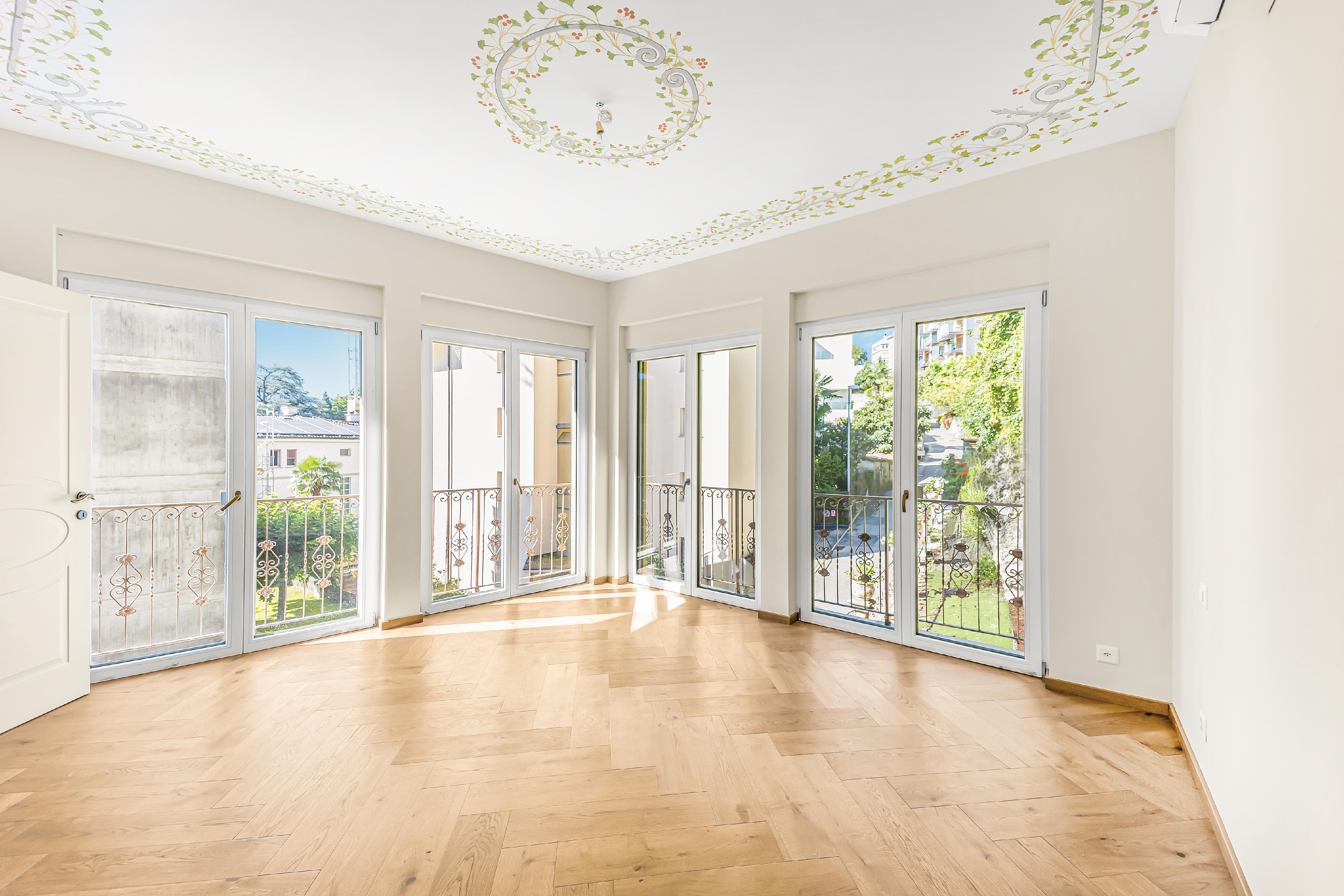 Heller, leerer Raum mit vielen Fenstern und dekorierter Decke