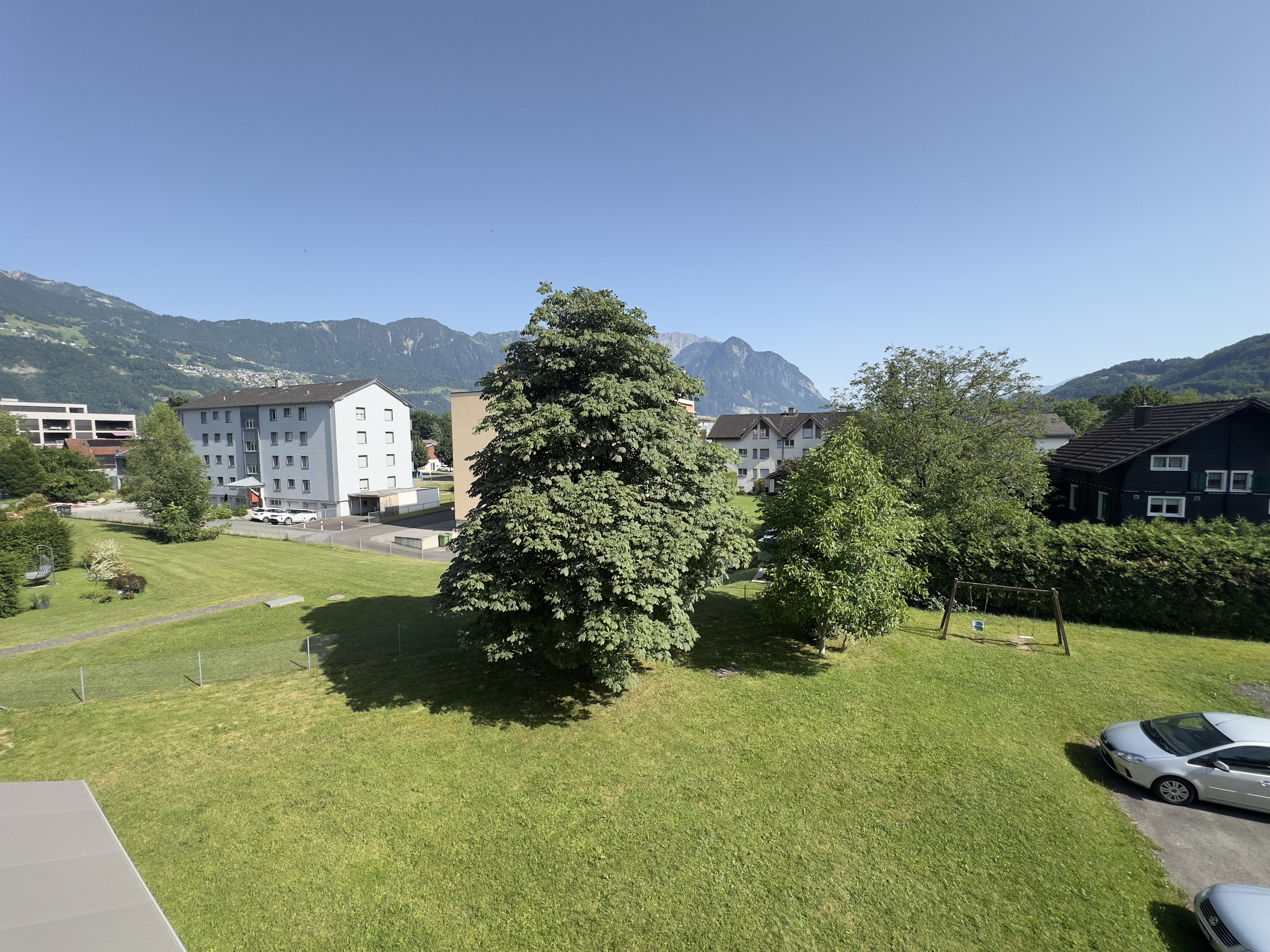 Blick über eine grüne Wohnanlage mit Bergpanorama