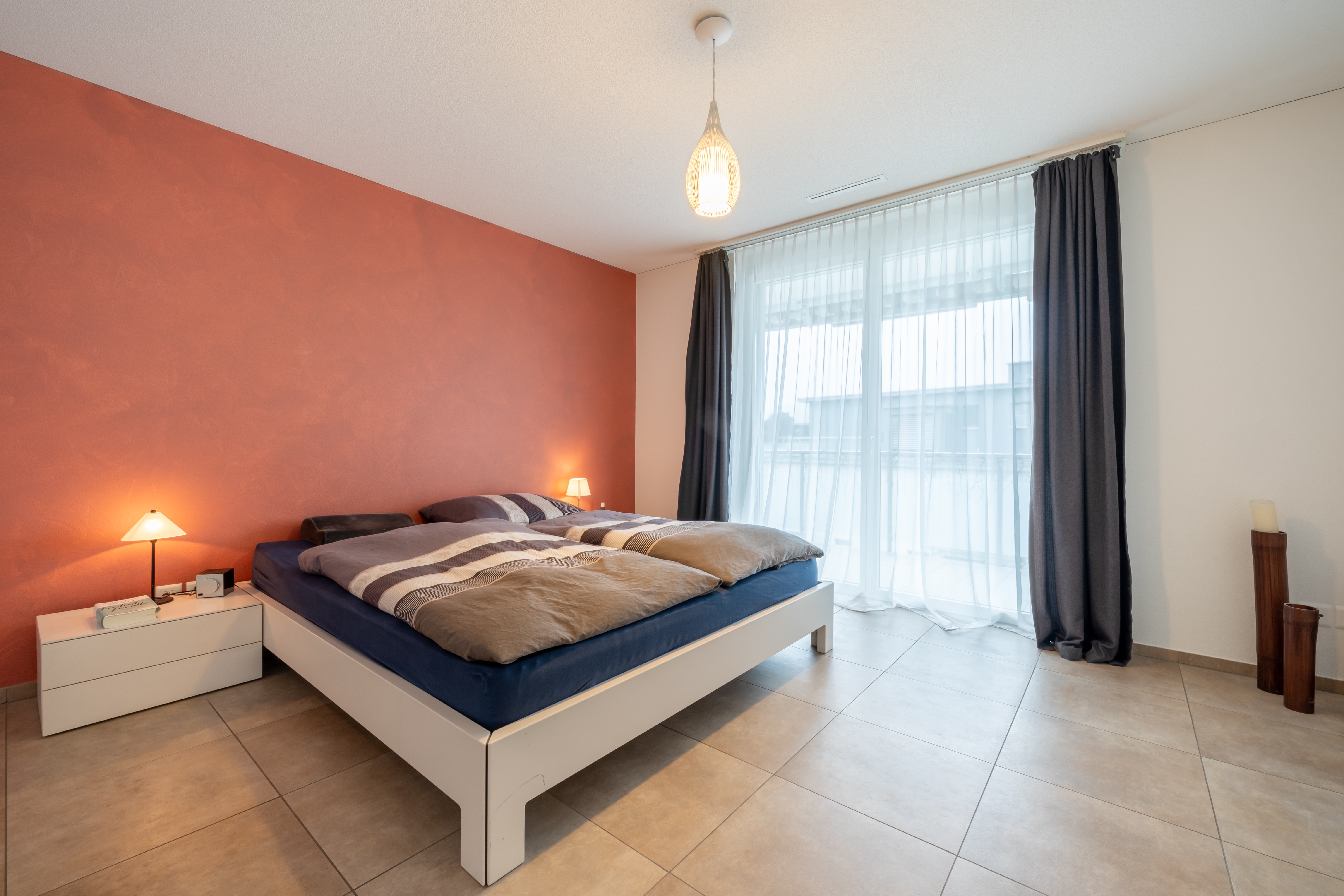 Modernes Schlafzimmer mit Doppelbett und großer Fensterfront