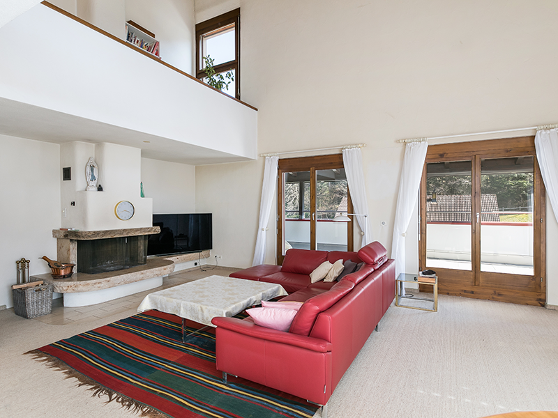 Offener Wohnbereich mit Kamin und rotem Sofa