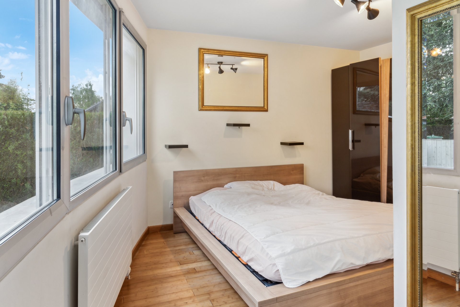Helles Schlafzimmer mit Bett und großen Fenstern