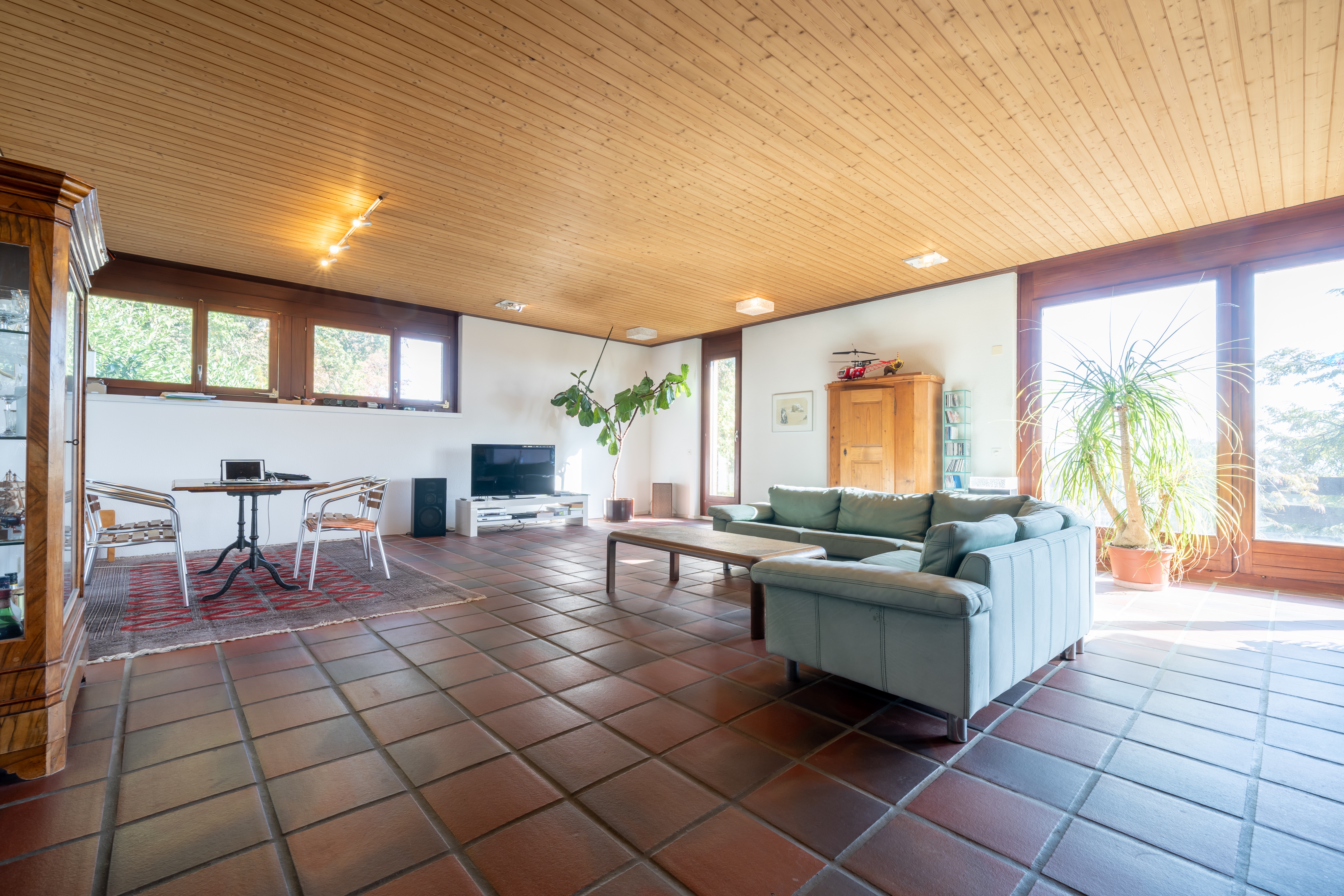 Großzügiges Wohnzimmer mit Terrakottafliesen und Holzdecke