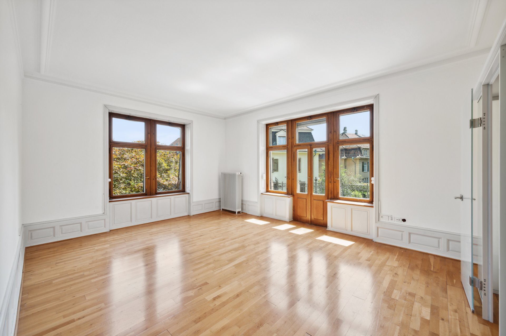 Heller leerer Wohnraum mit großen Holzfenstern