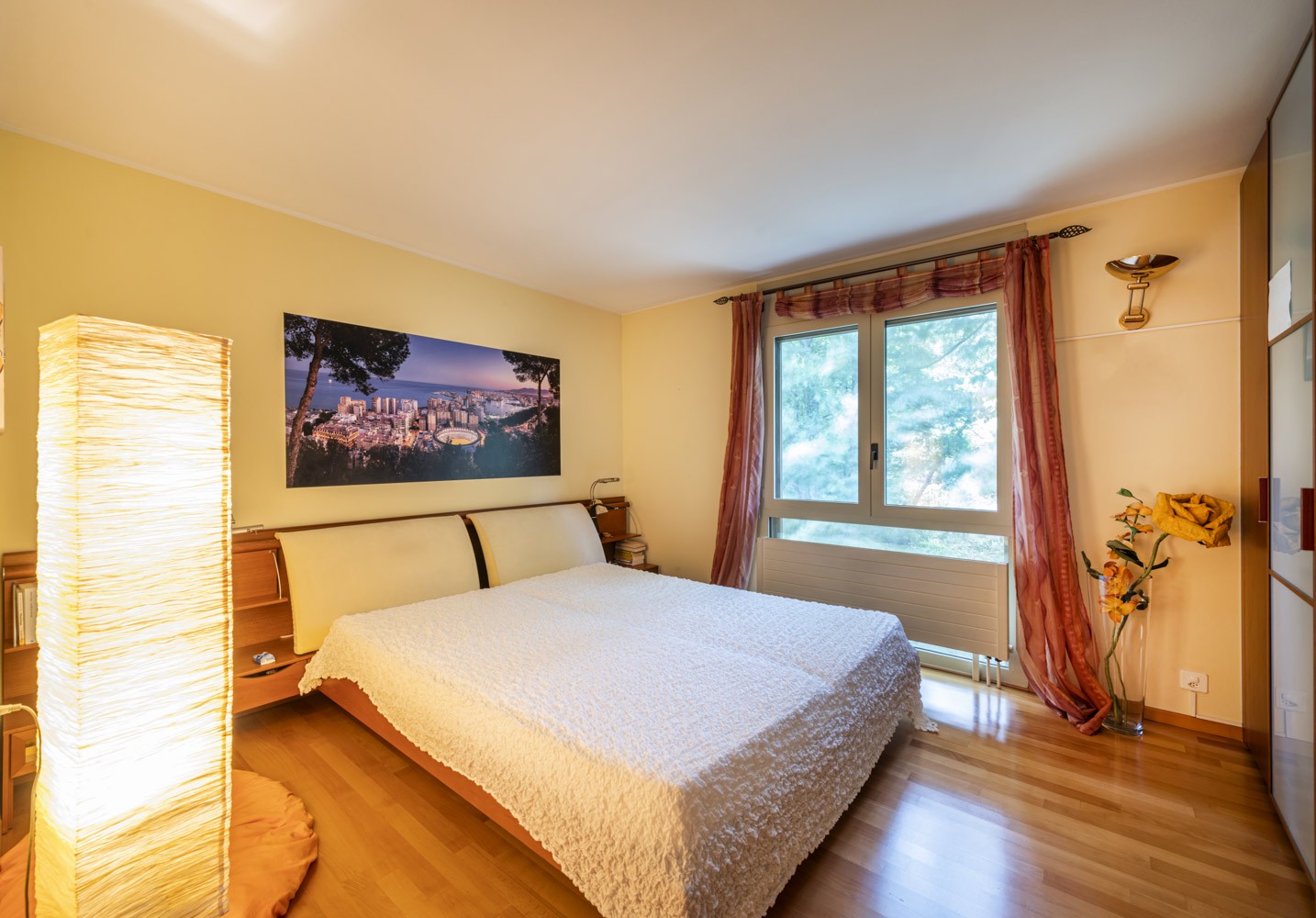 Helles Schlafzimmer mit Fensterfront und warmem Holzfußboden