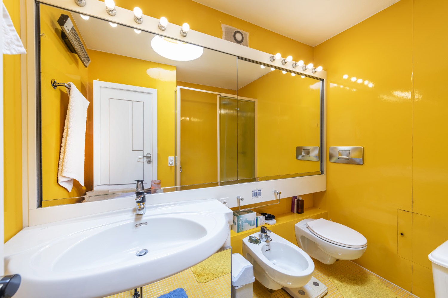 Gelbes Badezimmer mit großem Spiegel und Wand-WC