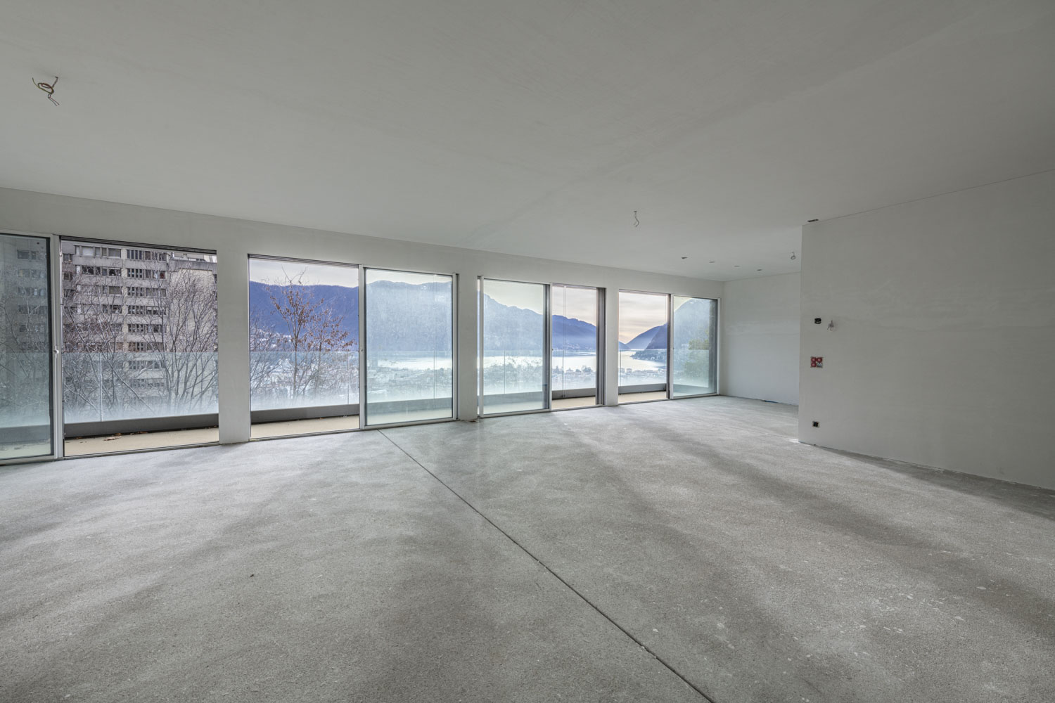 Großer leerer Wohnraum mit Panoramafenstern und Bergblick
