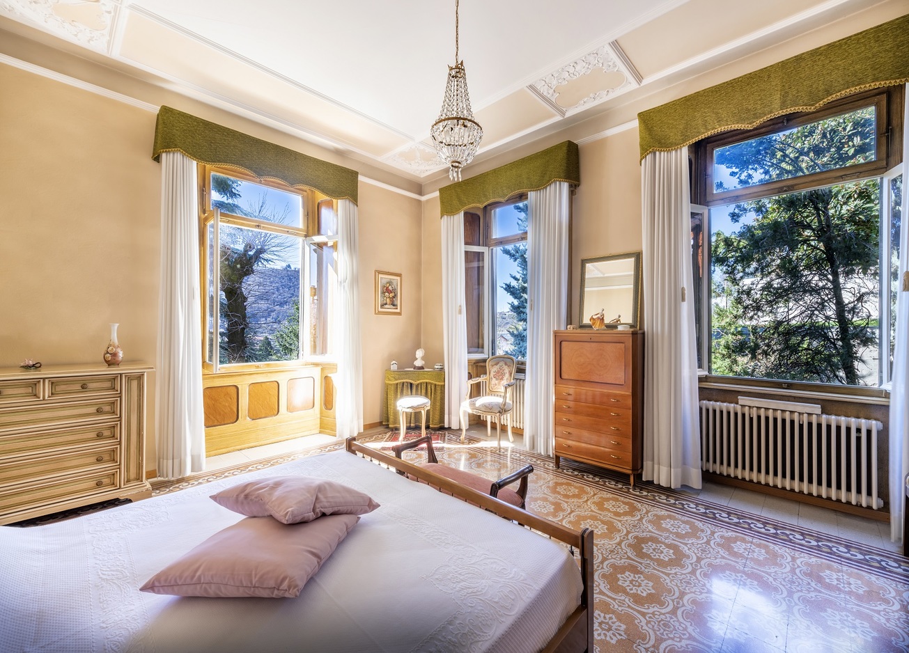 Klassisches Schlafzimmer mit großen Fenstern und Blick ins Grüne