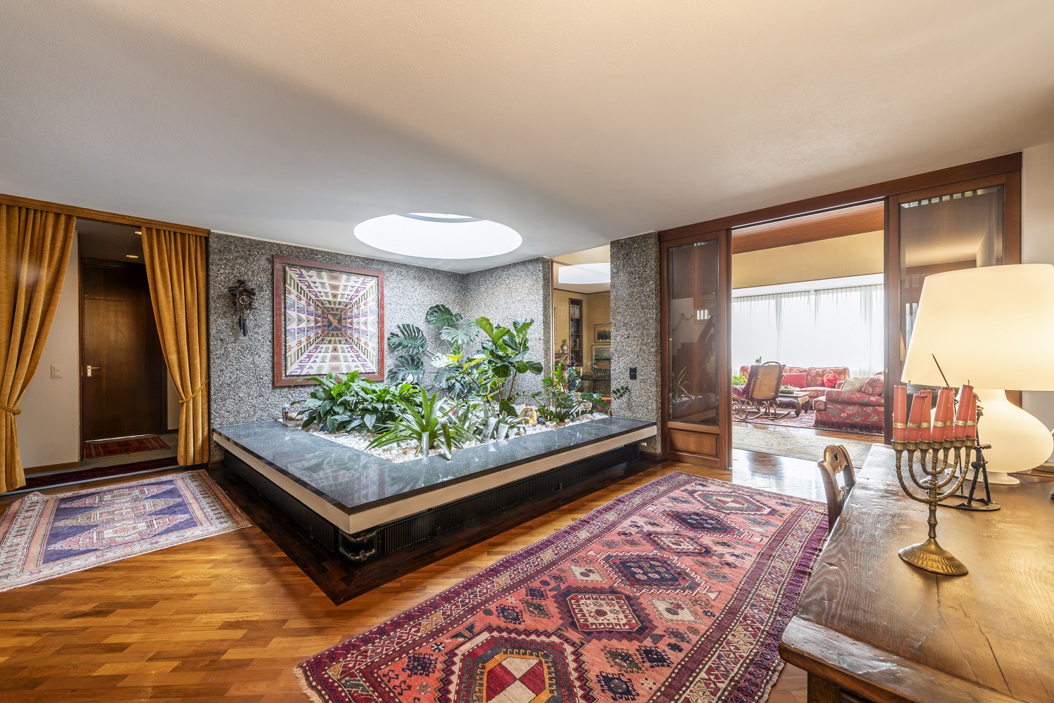Wohnzimmer mit zentralem Atrium und Blick in den angrenzenden Wohnbereich
