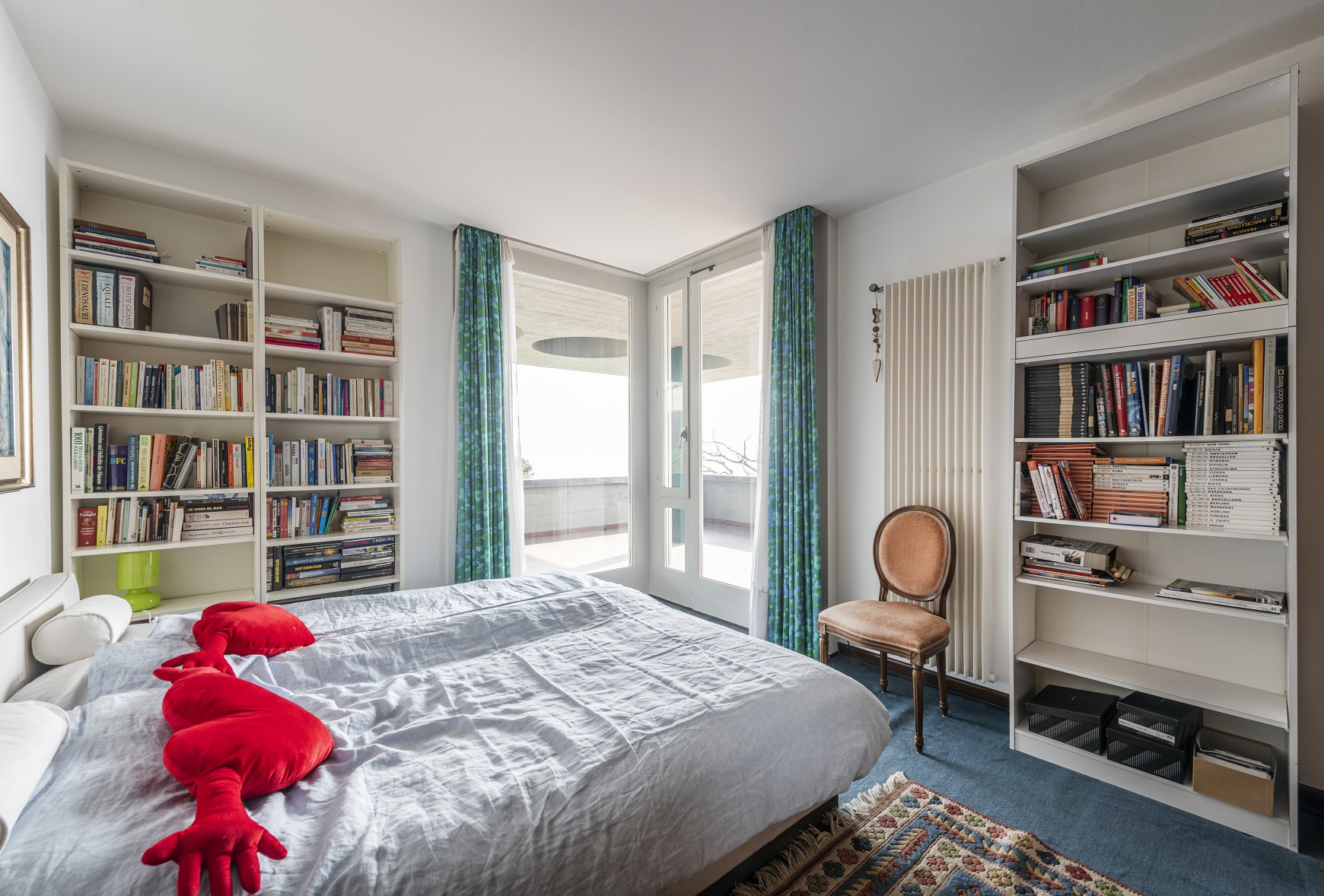 Schlafzimmer mit Balkon und Bücherregalen