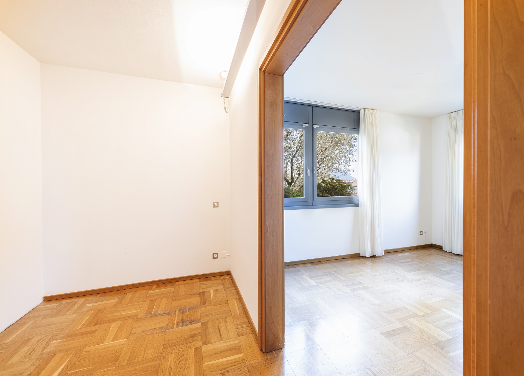 Helles Zimmer mit Parkett und Blick ins Nachbarzimmer