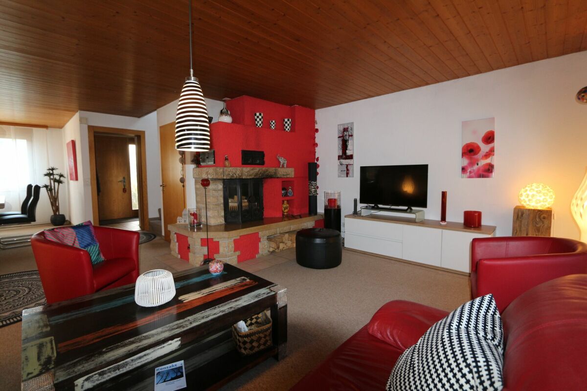 Wohnzimmer mit Kamin und roten Ledermöbeln
