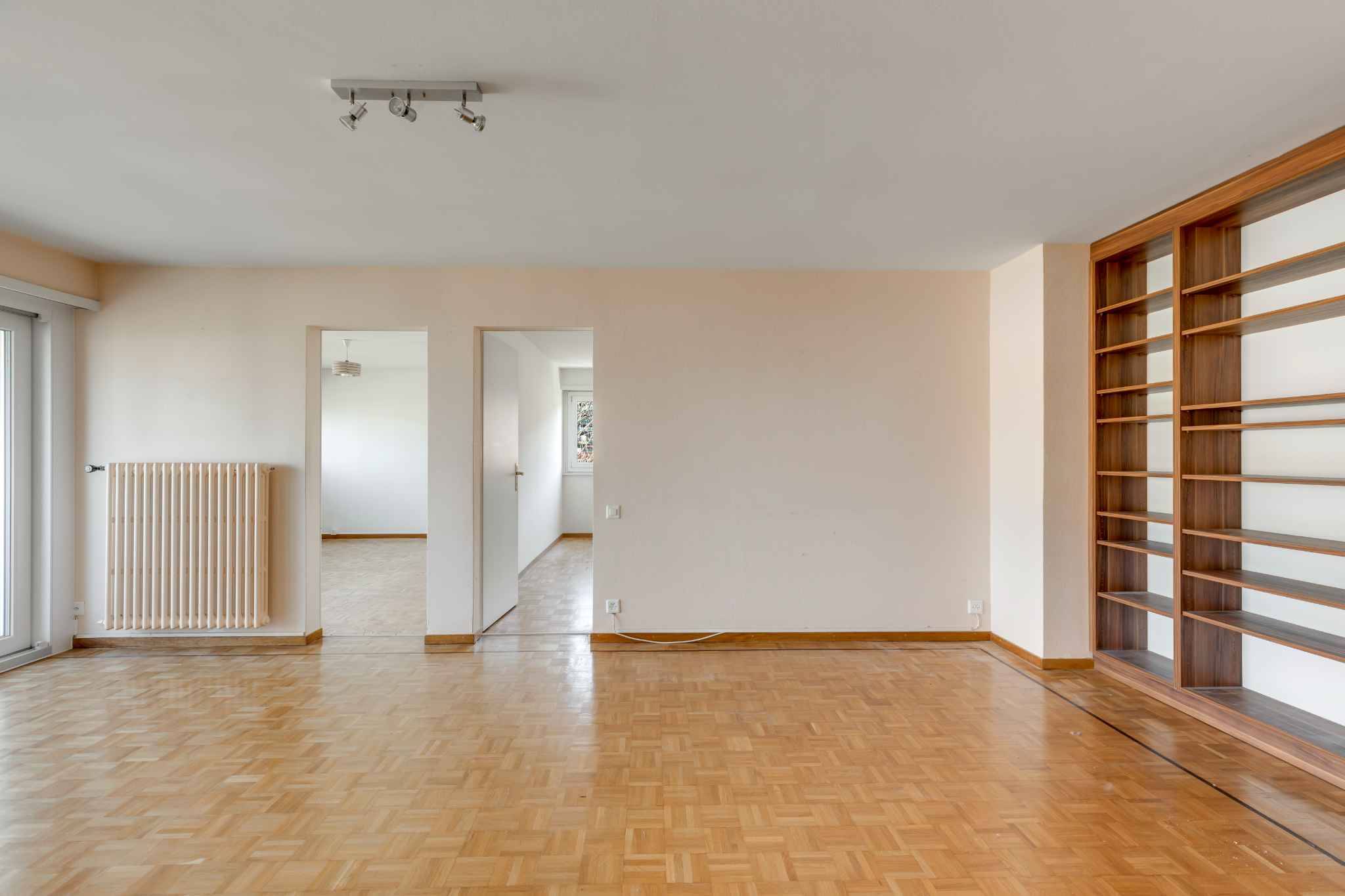 Leerer Wohnraum mit Parkett und Regalsystem