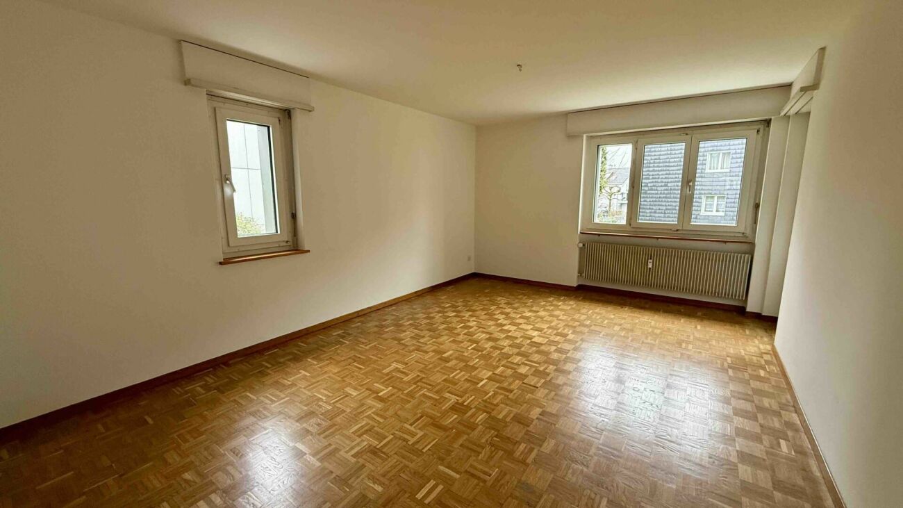 Leerer Wohnraum mit Parkett und Fenstern