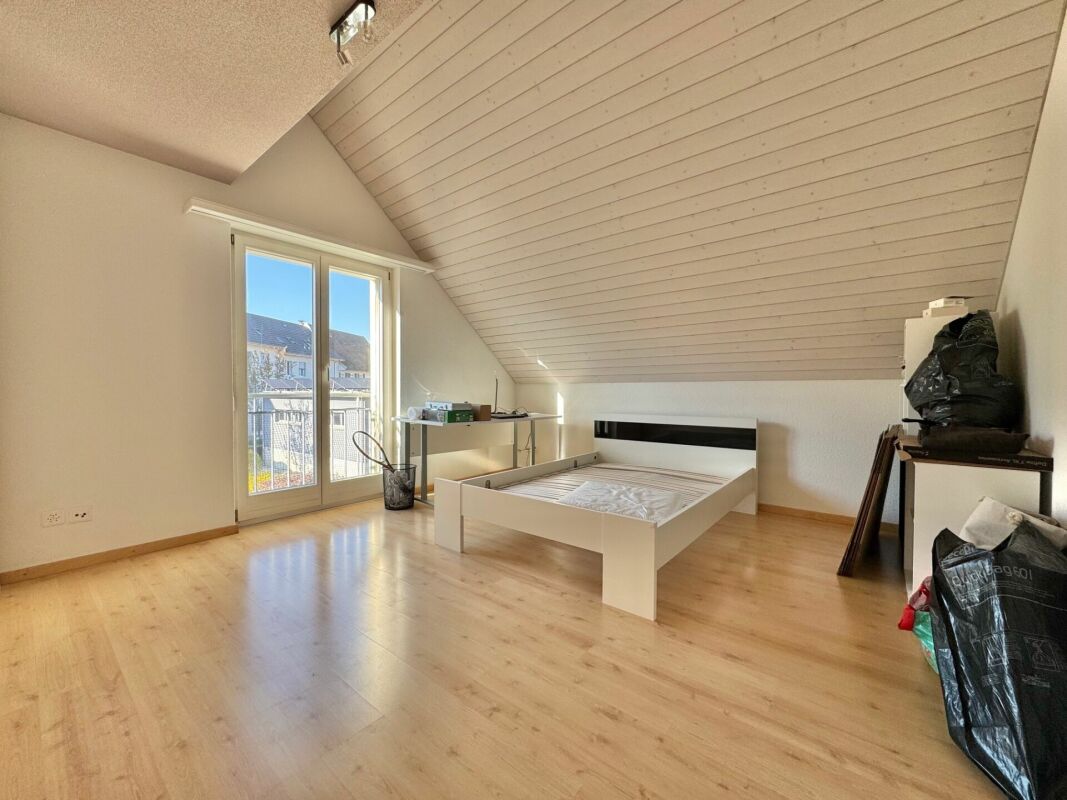 Dachzimmer mit Bett und Balkonfenster