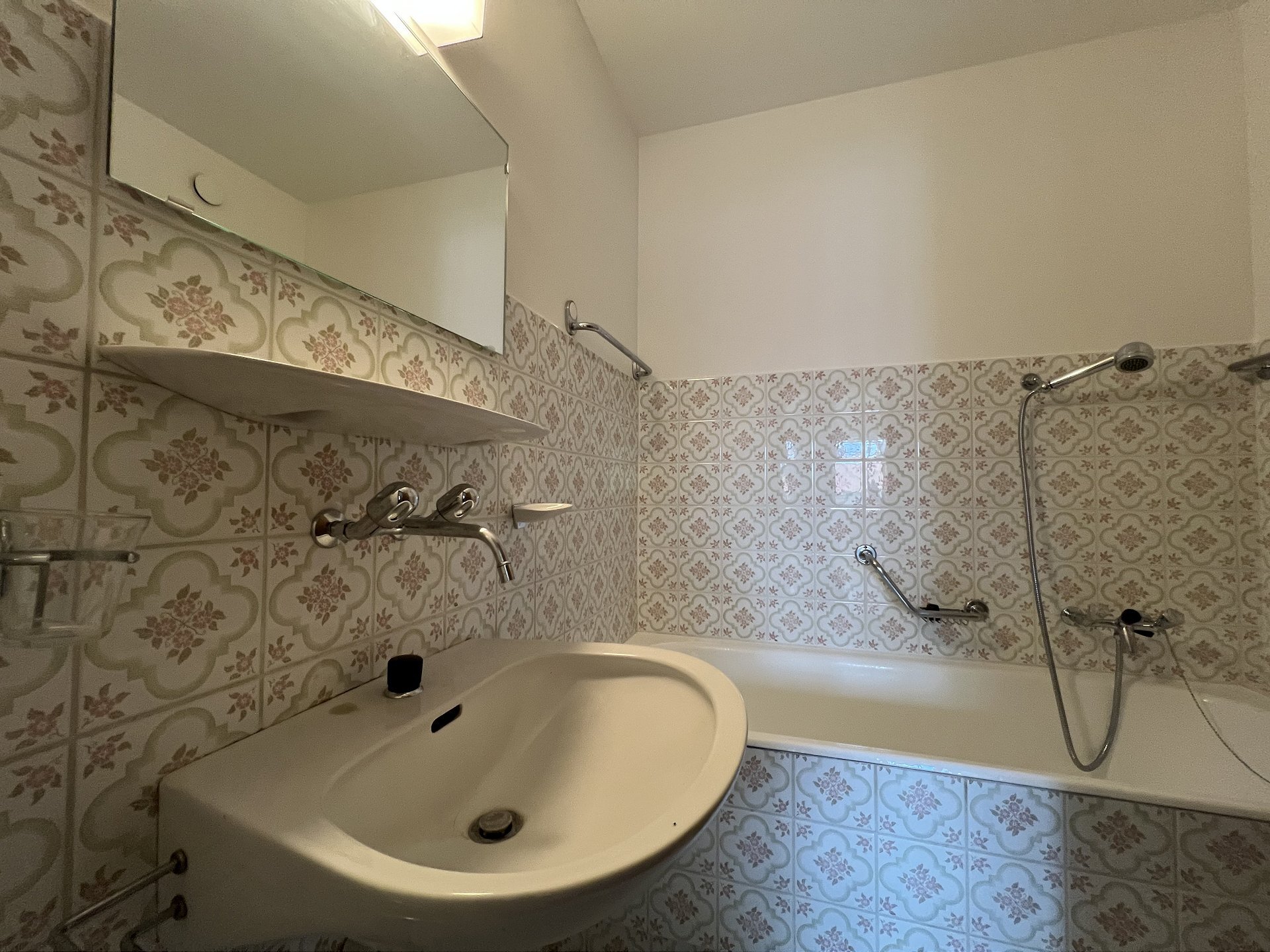 Badezimmer mit Wanne und floral gefliesten Wänden
