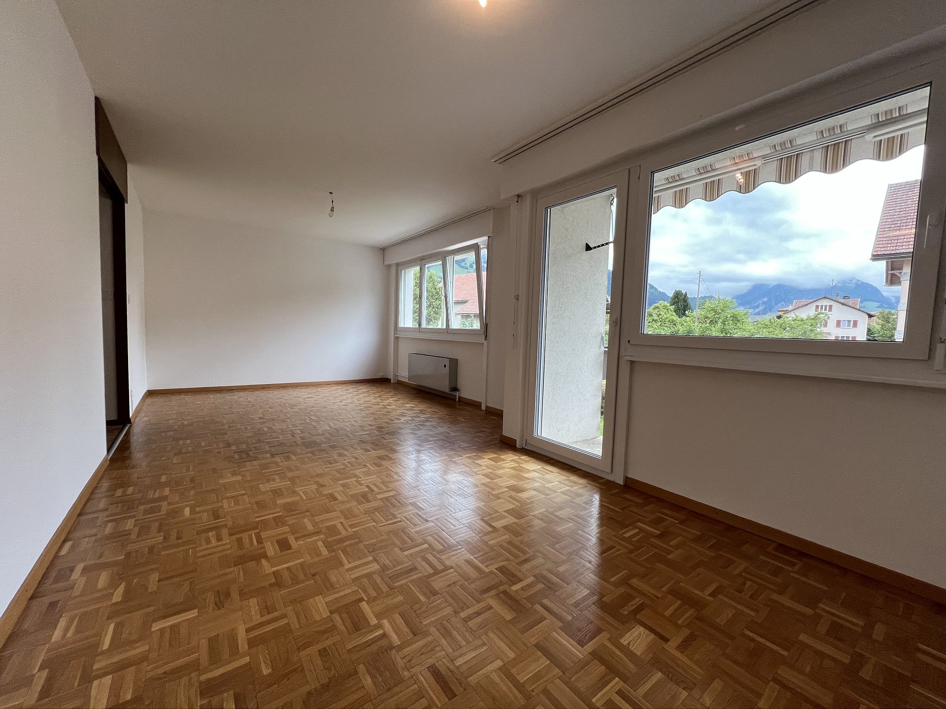 Leerer Wohnraum mit Balkon und Bergblick