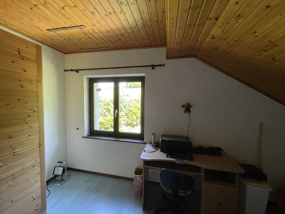 Dachzimmer mit Schreibtisch und Fenster