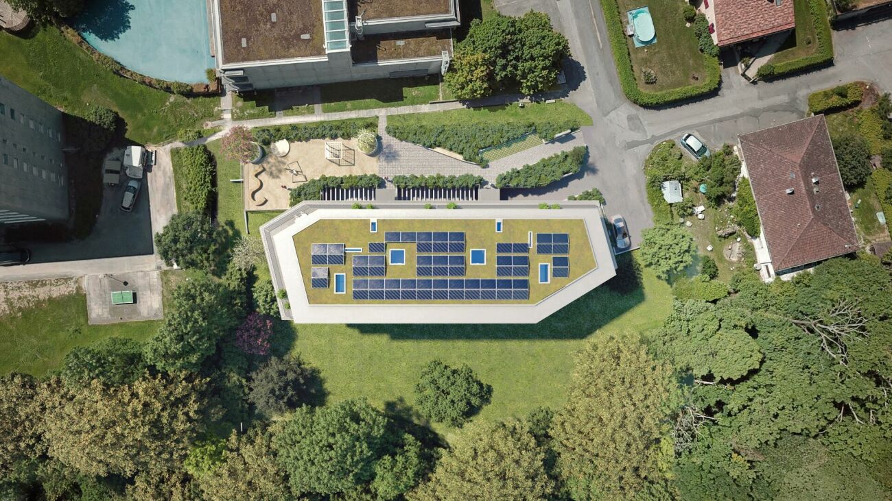 Luftaufnahme eines begrünten Gebäudedachs mit Solarmodulen