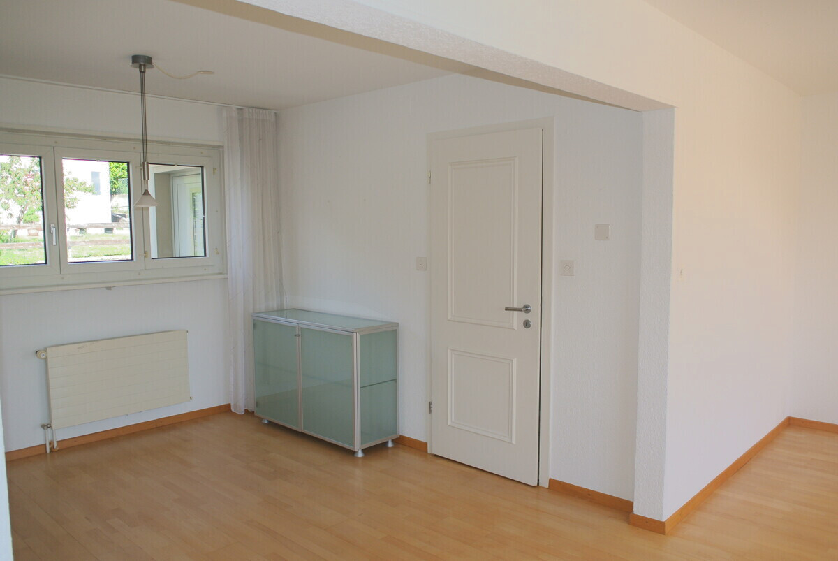 Heller Wohnraum mit Fenster, Tür und Heizkörper
