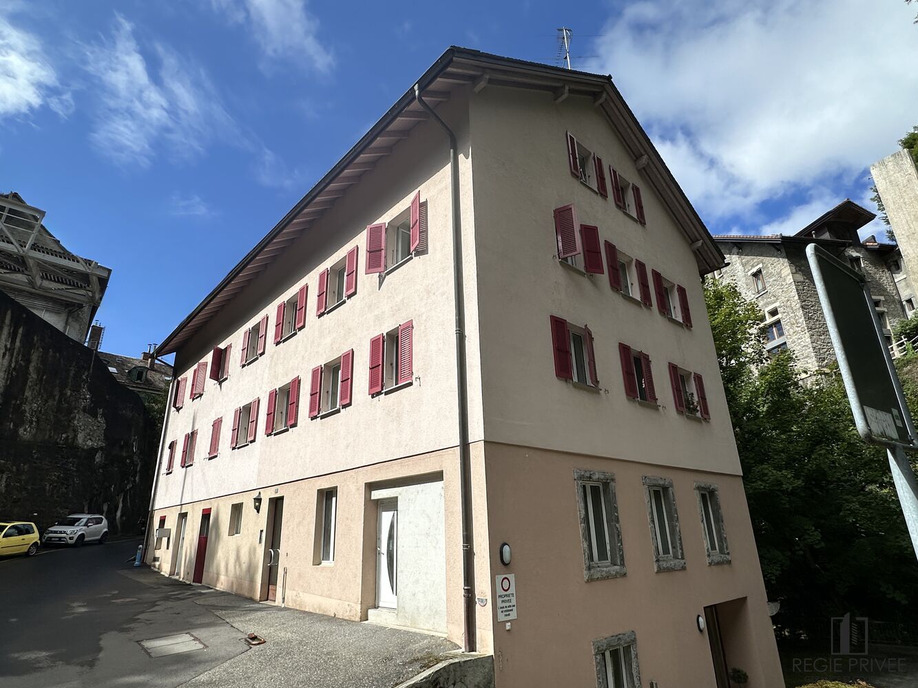 Mehrfamilienhaus mit pastellfarbener Fassade und roten Fensterläden
