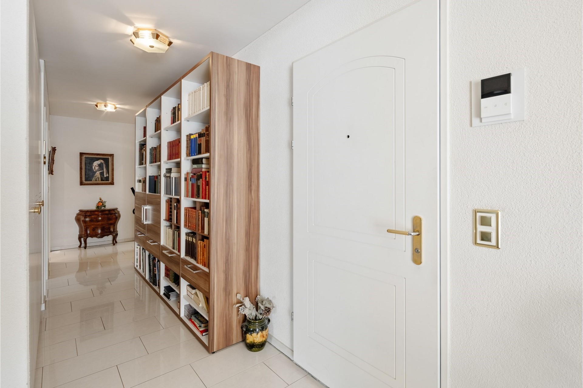 Heller Flur mit Bücherregal und Wohnungseingang