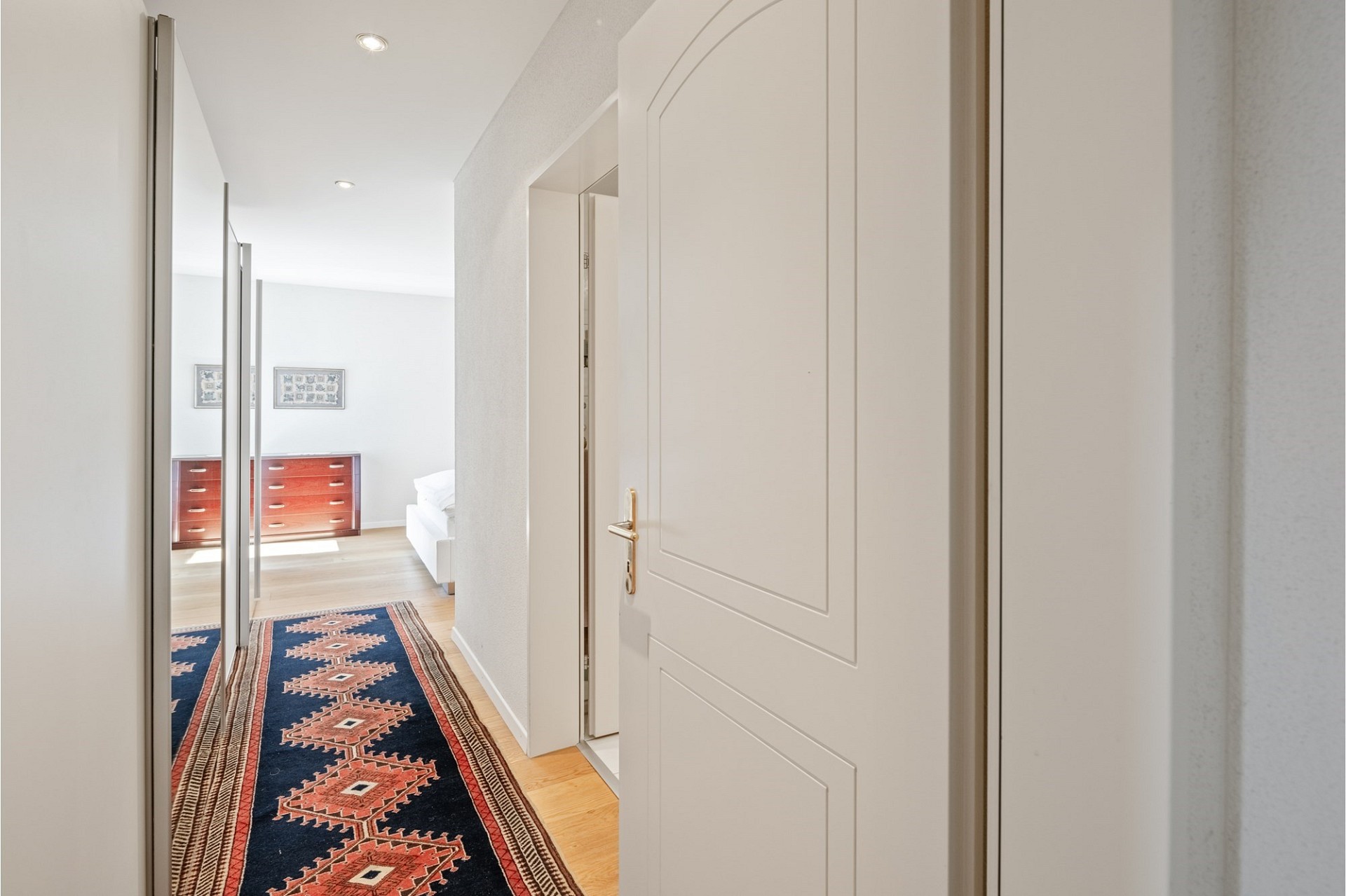 Heller Flur mit Teppichläufer und Blick in ein Schlafzimmer