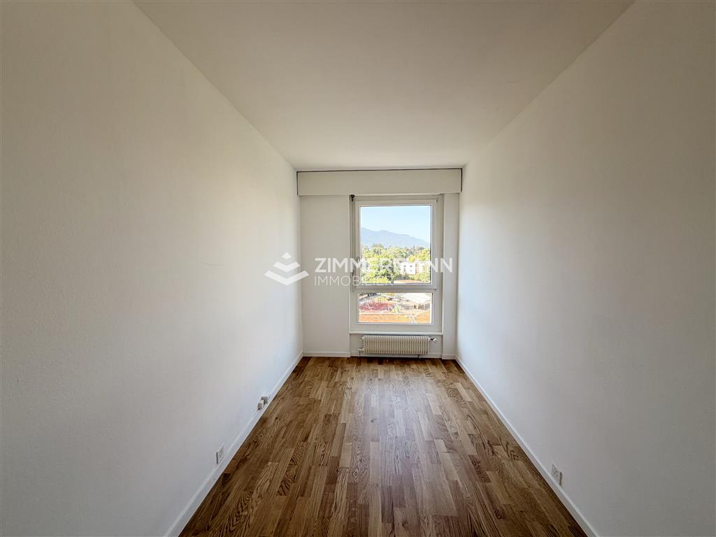 Schmaler, leerer Raum mit Fenster und Holzboden