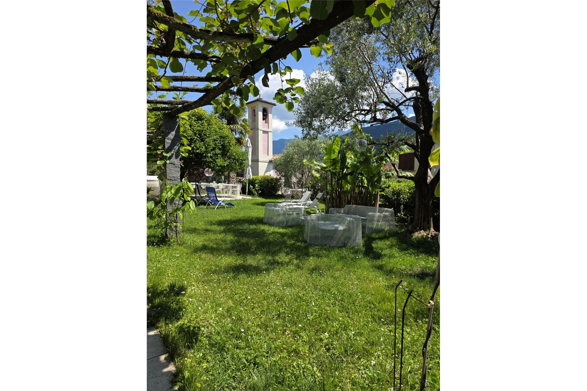 Sonniger Garten mit Sitzbereich und Blick auf Turm