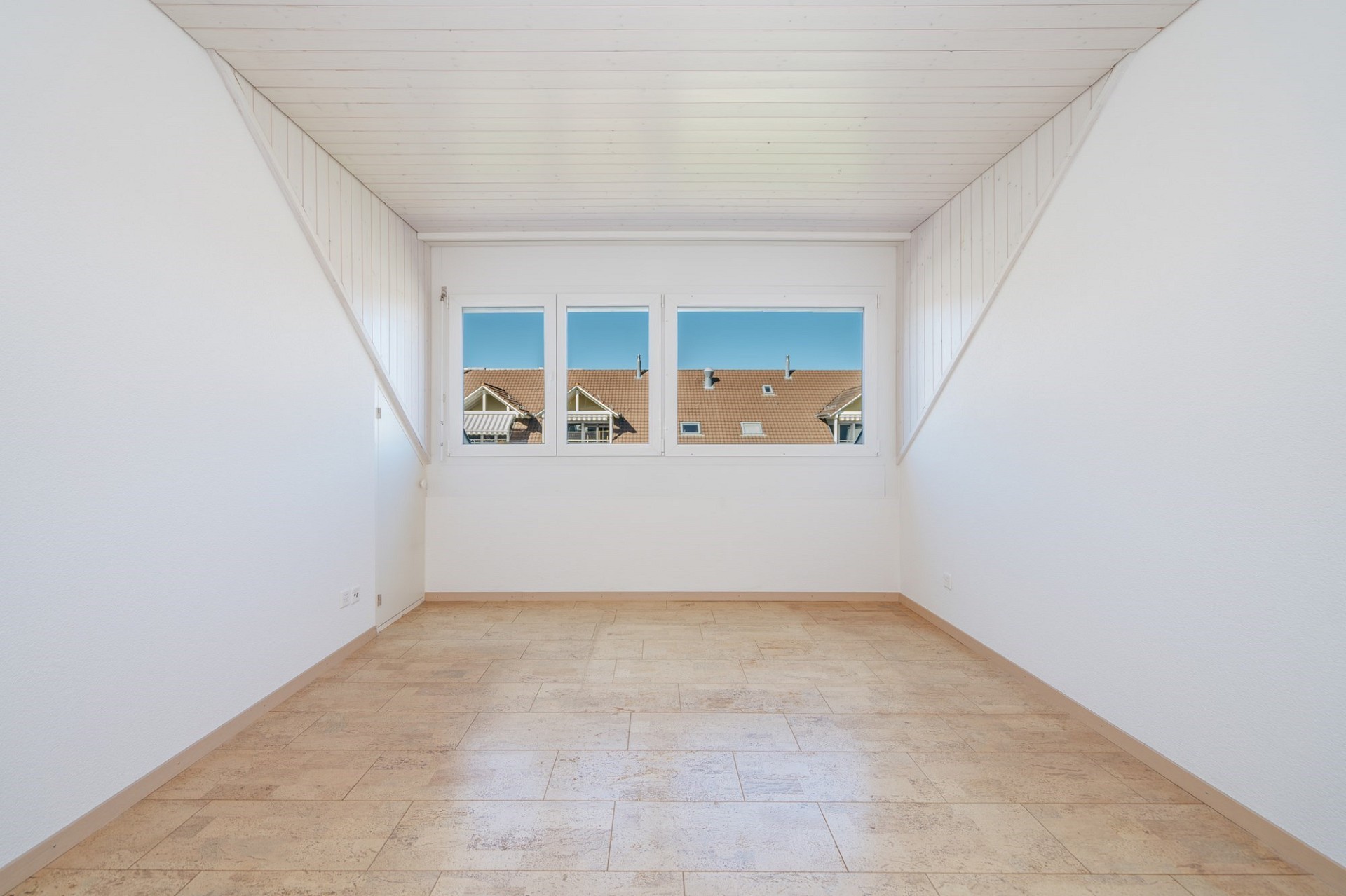 Heller leerer Raum mit Dachfenster-Atmosphäre und Blick auf Nachbarhäuser