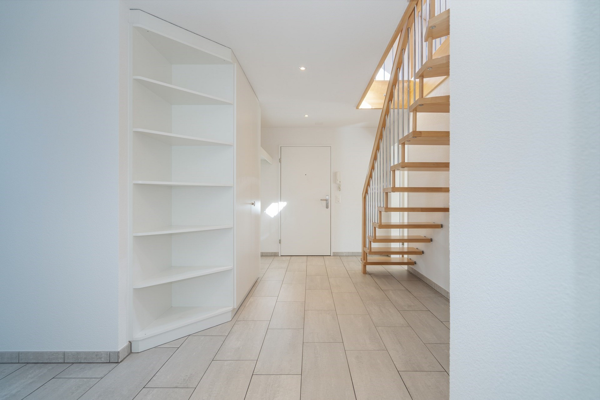 Heller Eingangsbereich mit Treppe und Einbauregal