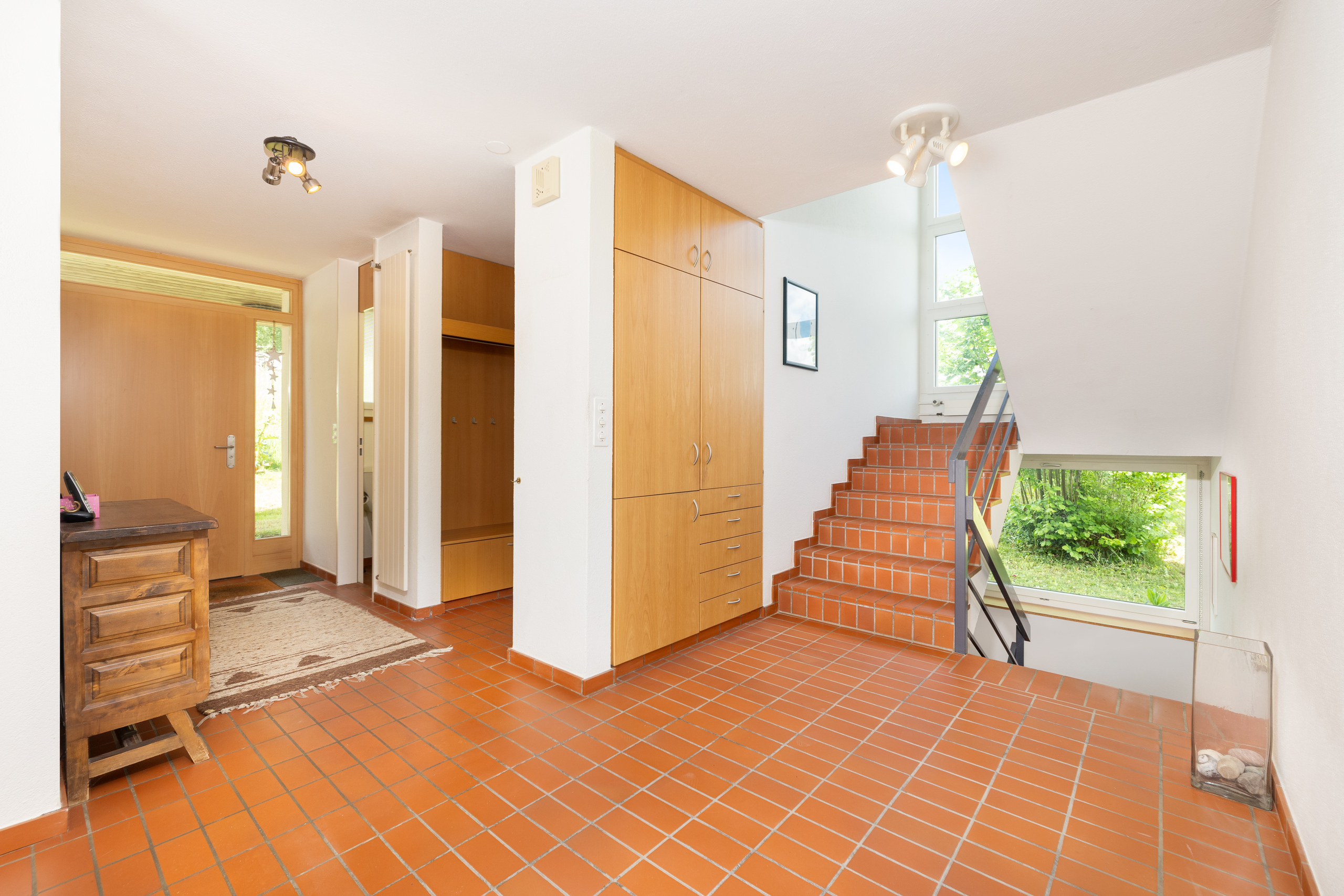 Heller Eingangsbereich mit Treppe und Terrakottafliesen